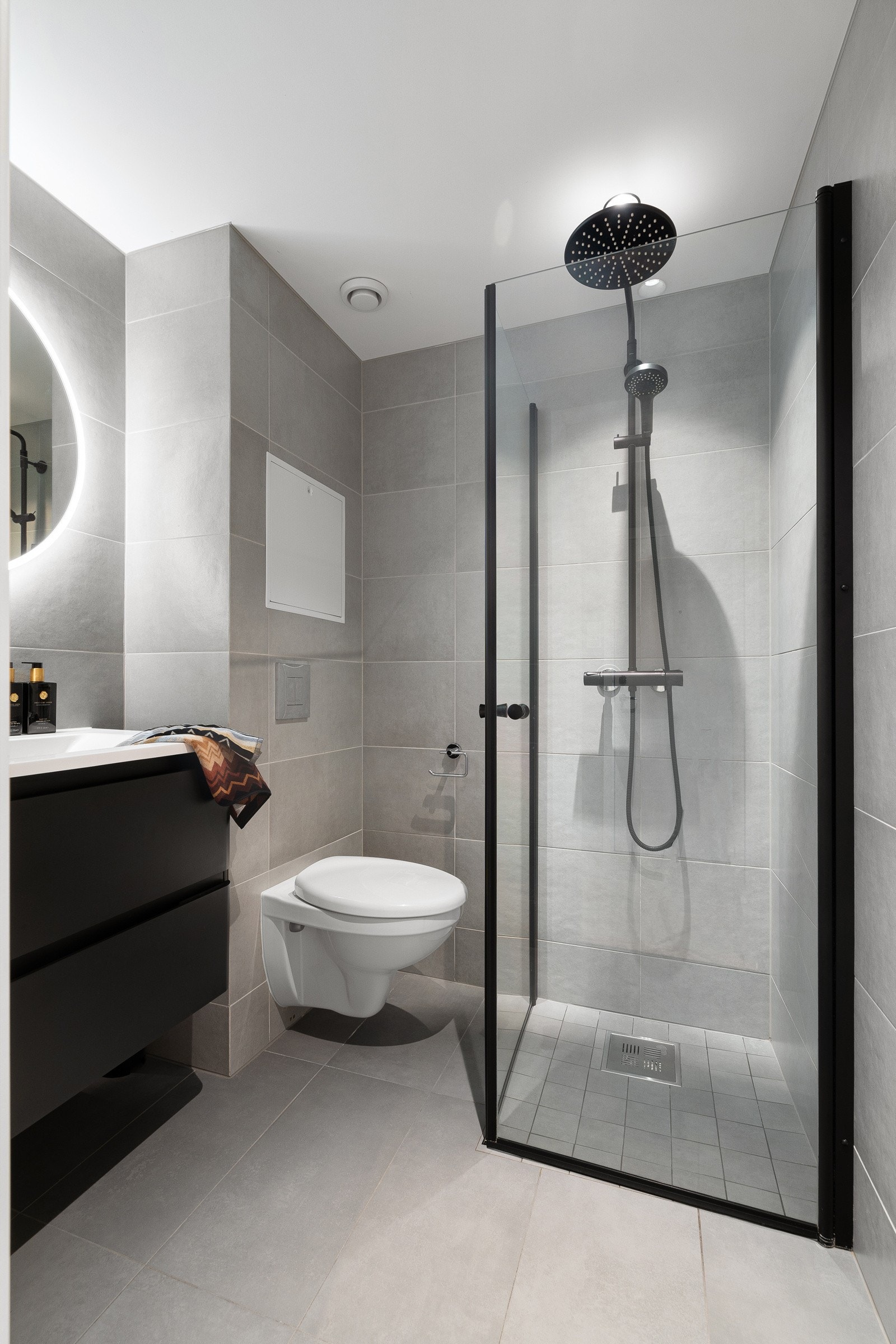 Dusjhjørne med innfellbare dører, vegghengt toalett og stilfull baderomsinnredning. Galleribilde