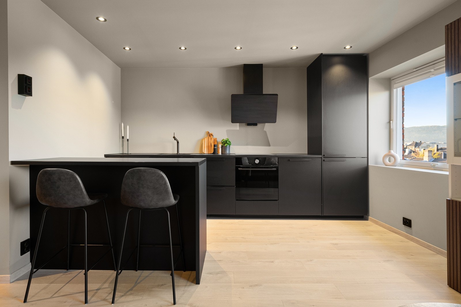 Åpen løsning mellom stue og kjøkken som er praktisk adskilt med kjøkkenøy og barløsning. Galleribilde