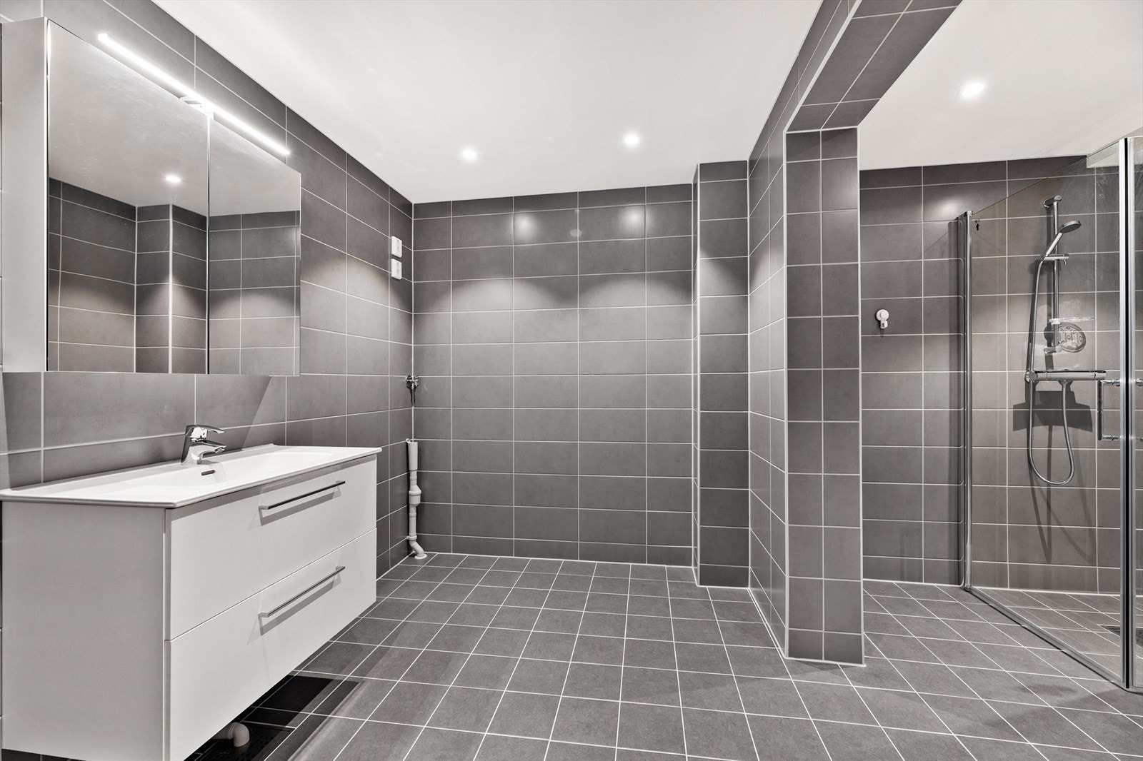 Lyst og romslig bad med himling med downlights. Galleribilde