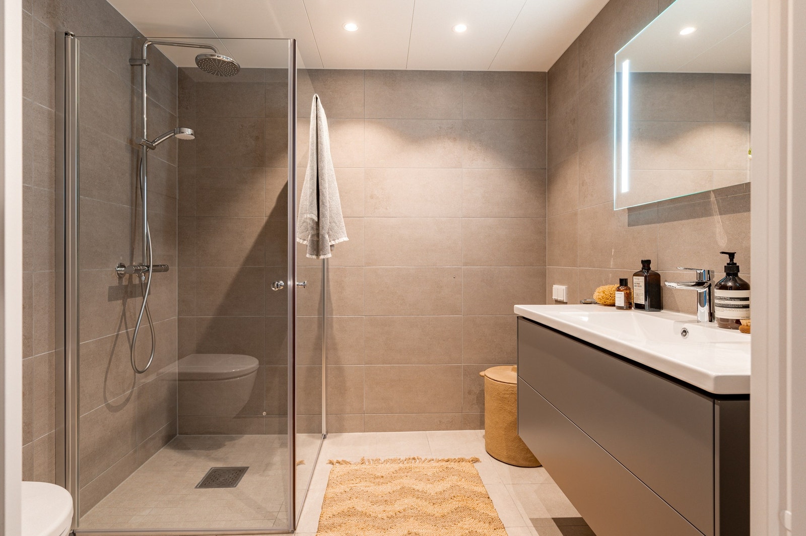 Innbydende og meget romslig bad med fliser, varme i gulv og downlights i himling Galleribilde