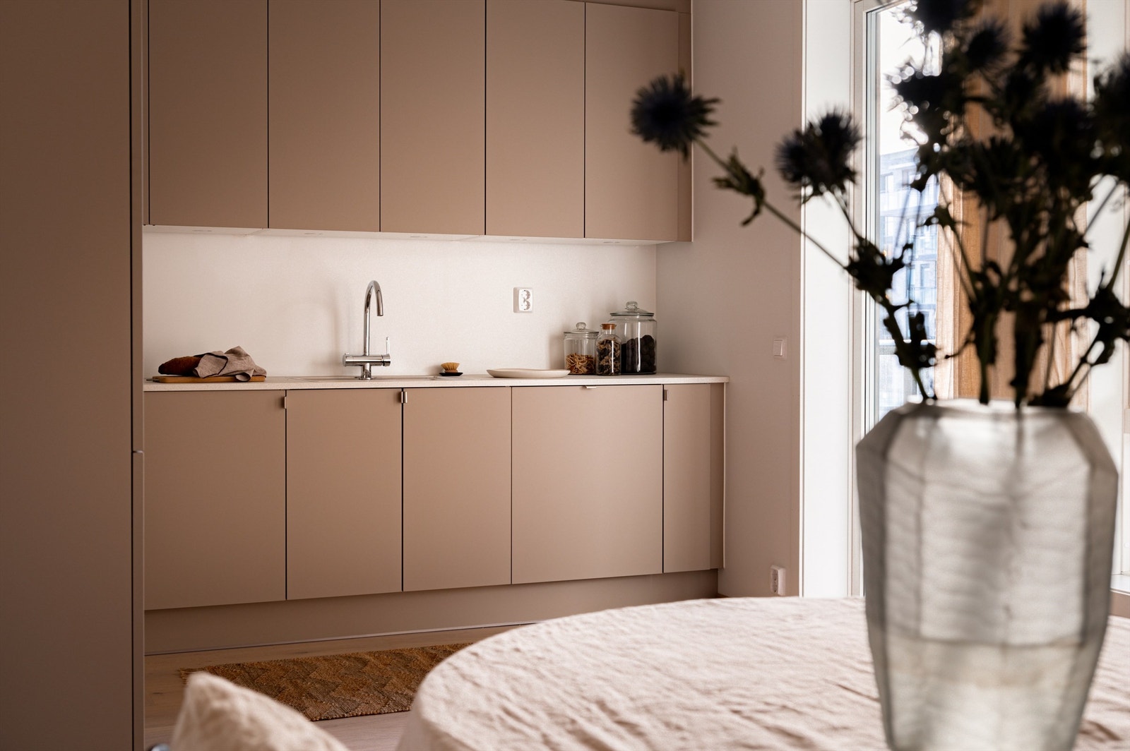 Lun innredning med laminat benkeplate, stikkontakter mellom benk og overskap samt nedfelt oppvaskkum med ett-greps armatur Galleribilde