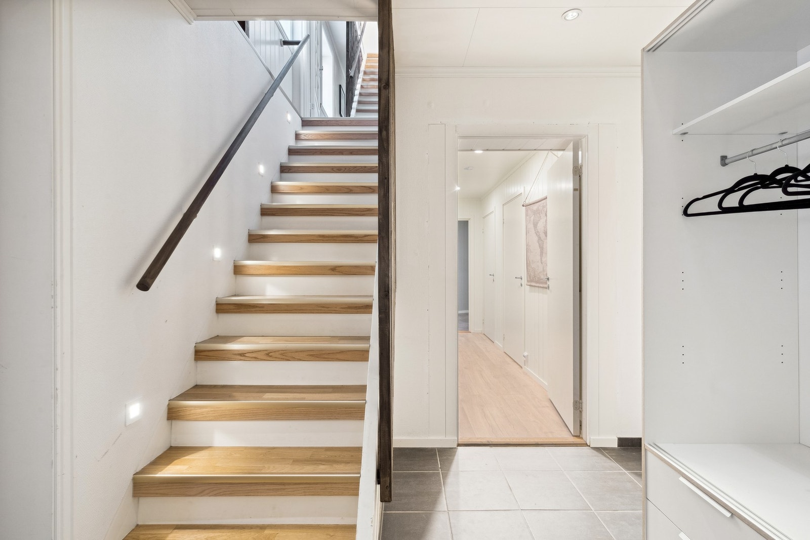 Velkommen inn! Her kan du gå opp trappen til 2. etasje eller gå videre inn gangen til to soverom og ett bad. Galleribilde