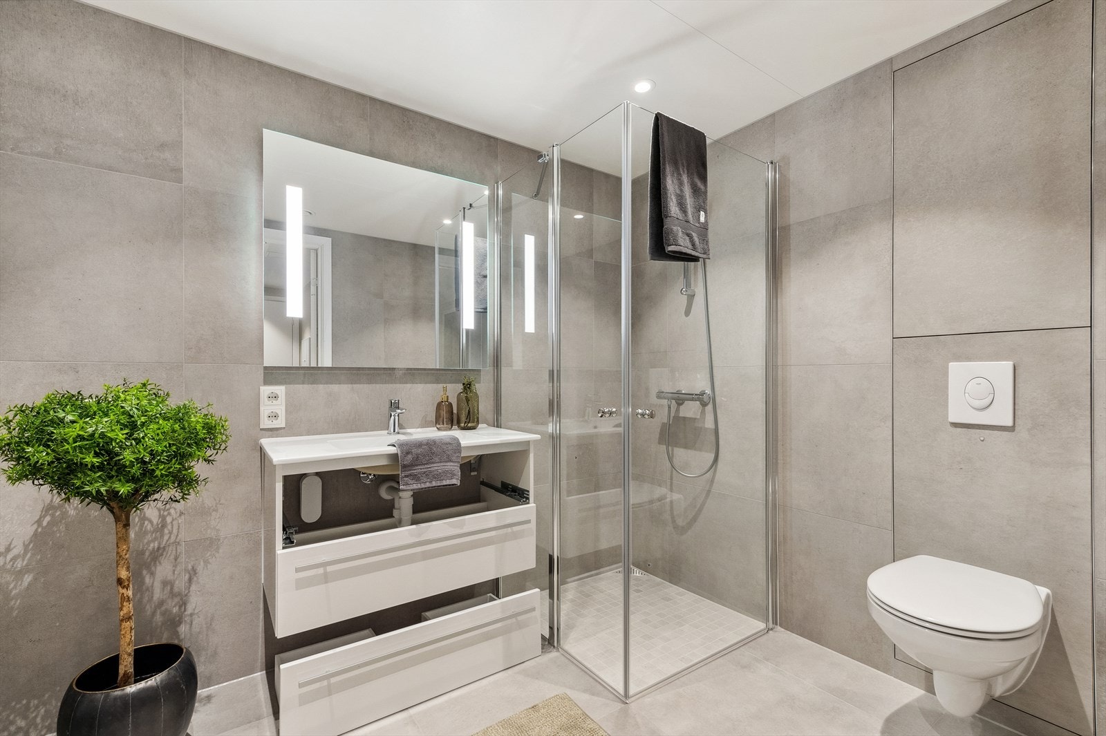 Delikat bad som er moderne innredet med store 60x60 fliser, downlights og gulvvarme. Galleribilde