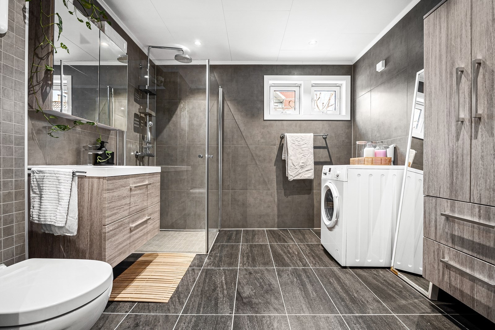 Stort moderne bad fra 2016 med servant med underskuffer, overskap med speildører, høyskap og svingbare dusjdører. Badet har også opplegg for vaske -og tørketrommel. Galleribilde
