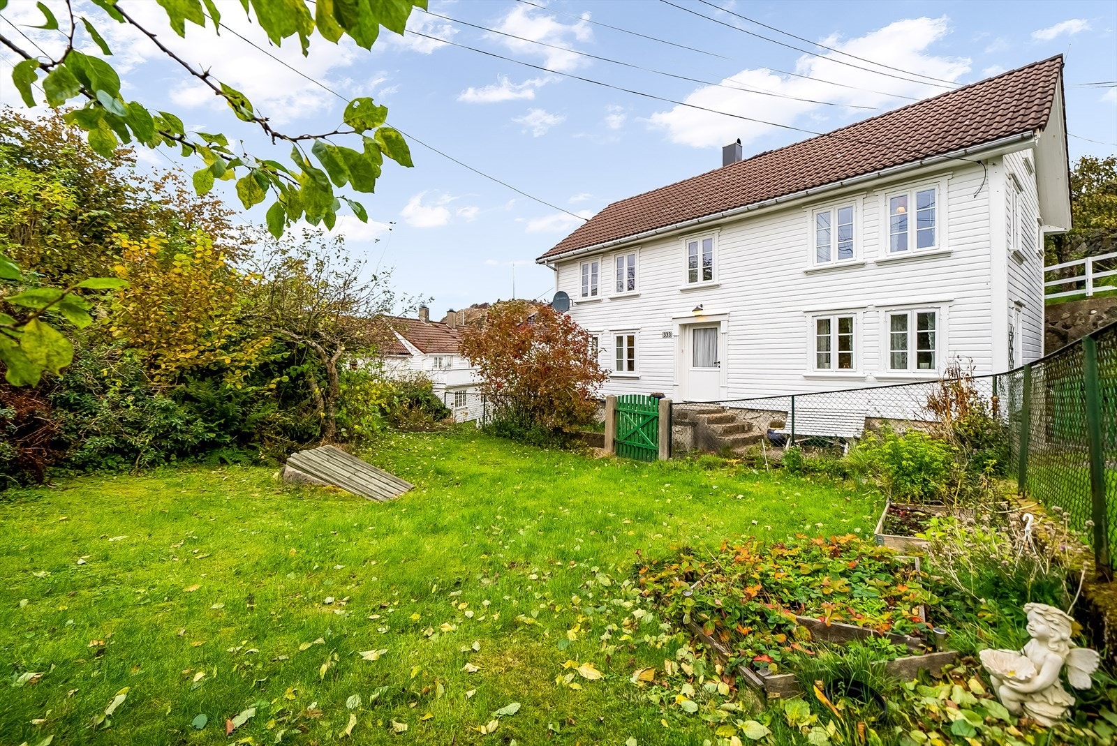 Tomta er opparbeidet med hage, plen, trær og prydbusker. Galleribilde