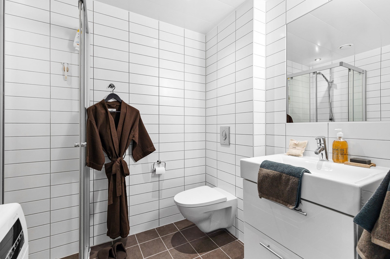 Vegghengt servantskap med ovenpåliggende servant og ett-greps armatur. Vegghengt toalett med innebygget sisterne. Galleribilde