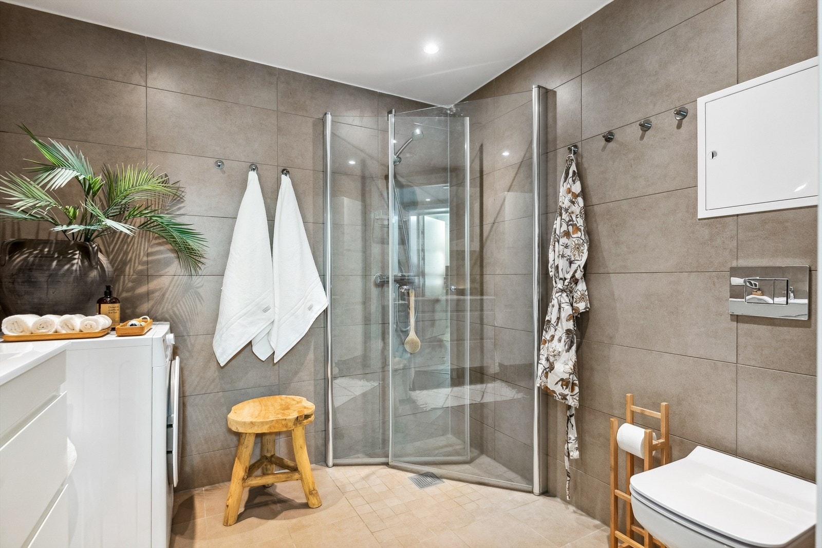 Badet er utstyrt med romslig dusjhjørne, vegghengt toalett, samt god plass til vaskemaskin og tørketrommel. Galleribilde