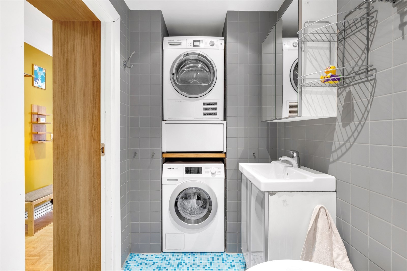 Baderomsinnredning bestående av benkeskap med frostede fronter, veggskap med speilfronter over servant. Galleribilde