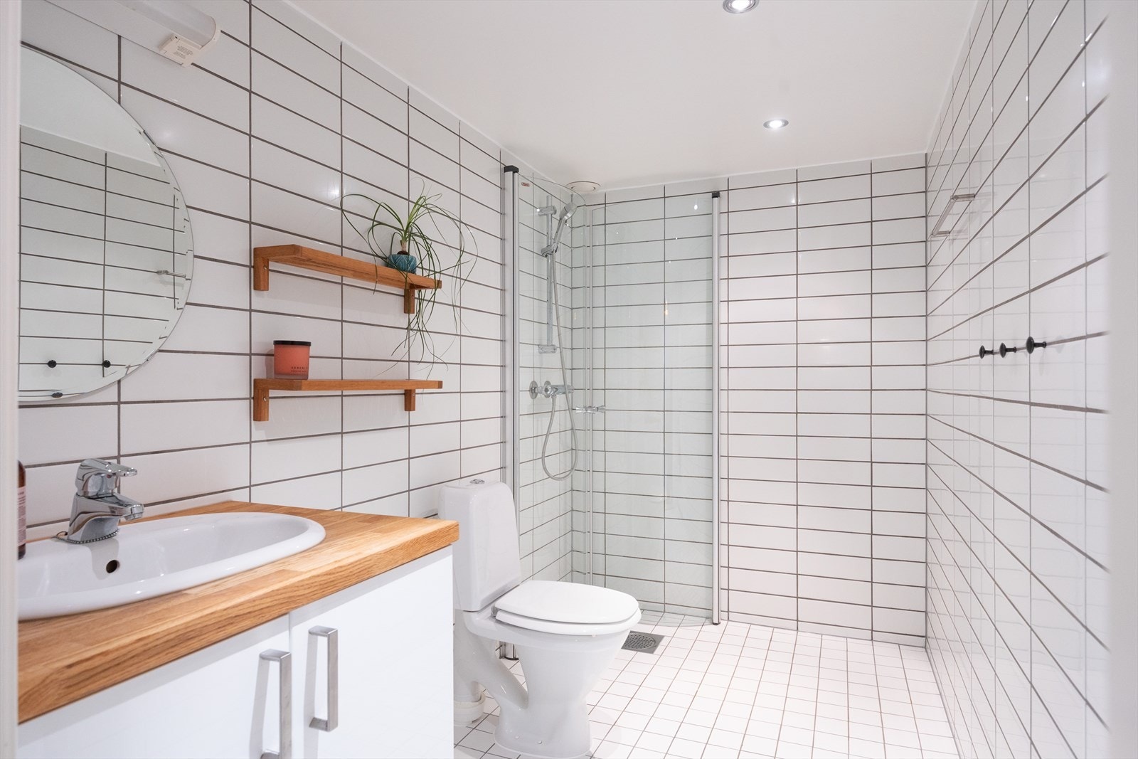 Badet består av downlights i tak, servantskap, gulmontert toalett og dusjnisje med innfellbare glassdører Galleribilde