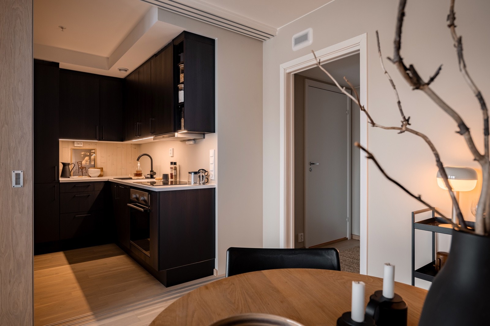 Helt nytt og moderne HTH-kjøkken fra 2023 med god skap- og benkeplass. Innredningen har glatte fronter med sort tre-look, lys laminert benkeplate med nedfelt sort oppvaskkum og sort armatur. Praktisk med takhøye overskap med belysning under. Galleribilde