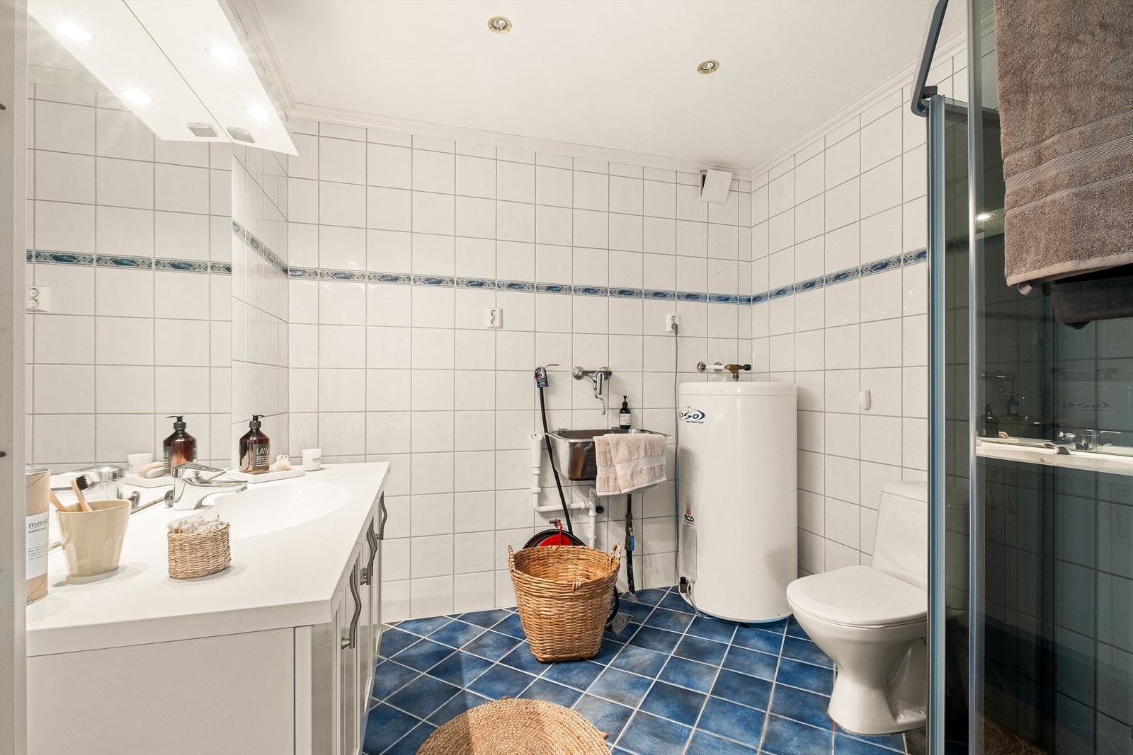 Badet inneholder toalett, helstøpt servant, skuffer under servant med profilerte fronter og dusjdører i klart glass. Det er selvsagt opplegg for vaskemaskin! Galleribilde
