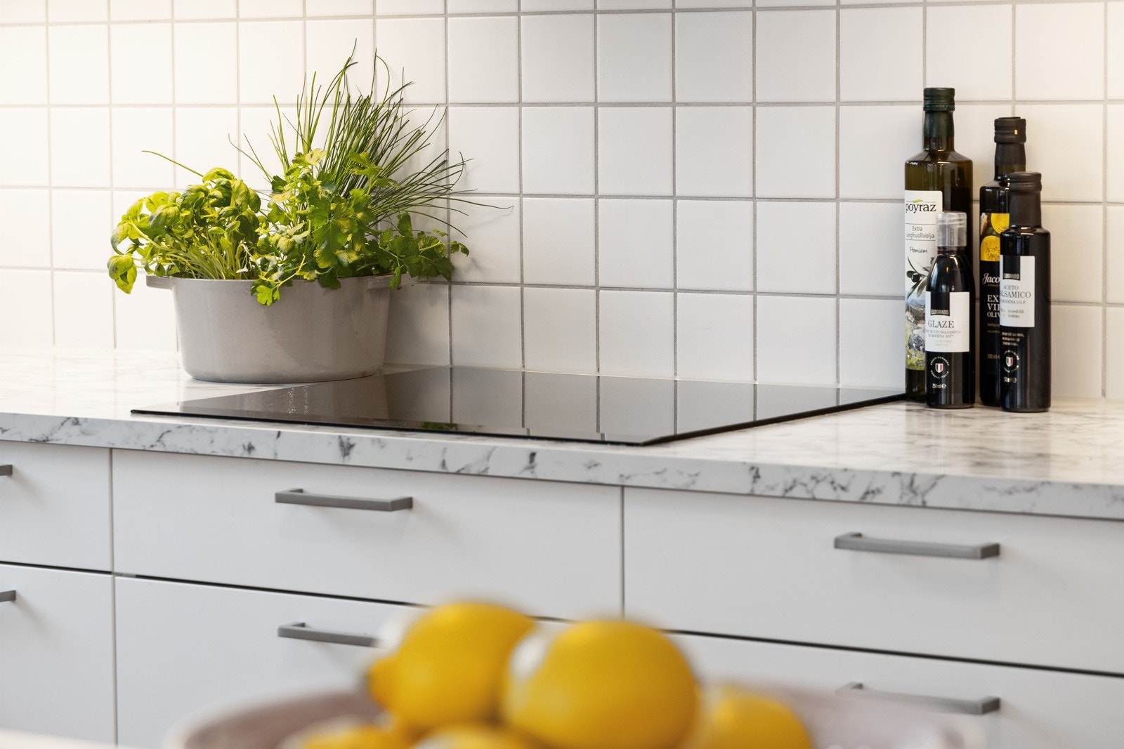 Kjøkkeninnredning med hvite, slette fronter og god oppbevarings- og benkeplass. Galleribilde