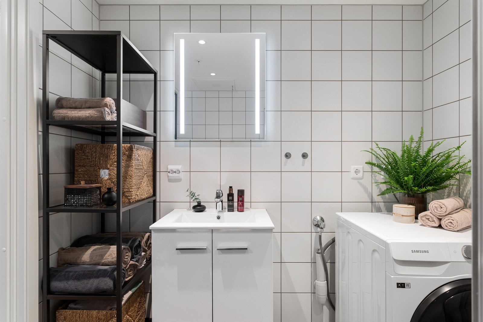 Badet er utstyrt med vegghengt toalett, servantinnredning, dushjørne med infellbare glassdører, samt opplegg for vaskemaskin. Galleribilde