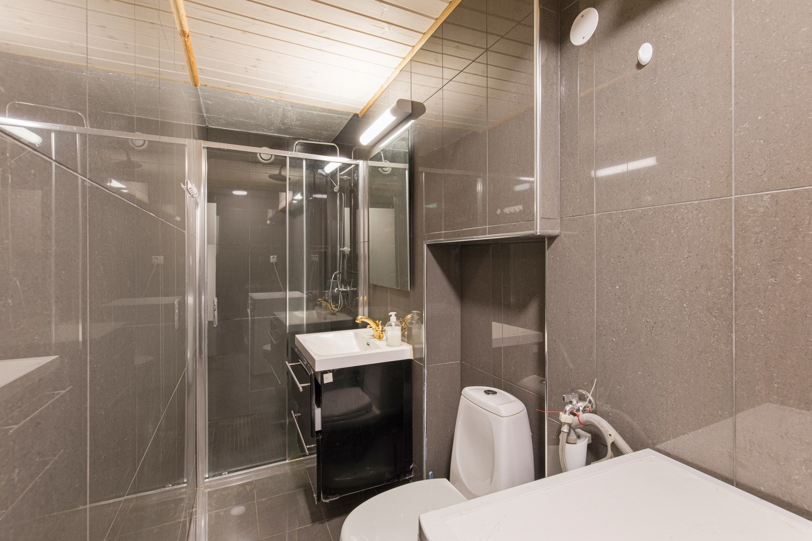 Helfliset bad med varmekabler i gulv. Rommet er utstyrt med innredning, dusj med dusjvegger, toalett og opplegg for vaskemaskin/tørketrommel. Galleribilde