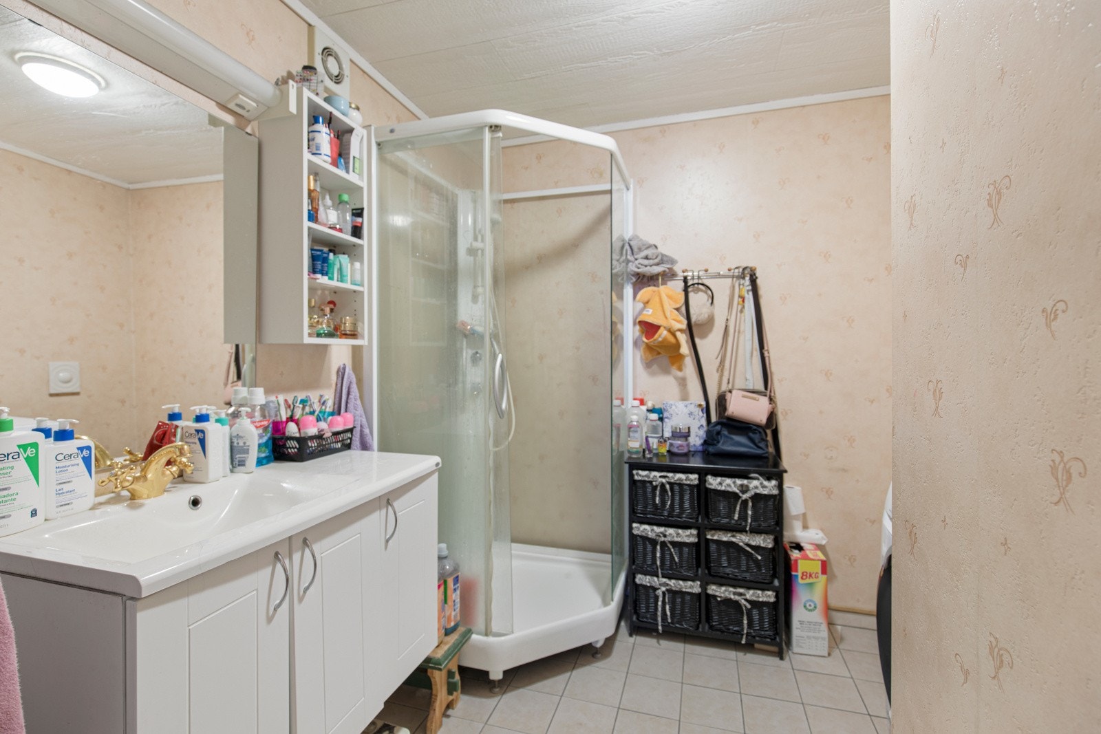 Badet i leiligheten har flis på gulv, tapet på vegger, varmekabler, baderomsinnredning, dusjkabinett, vegghengt toalett og opplegg for vaskamaskin/tørketrommel. Galleribilde