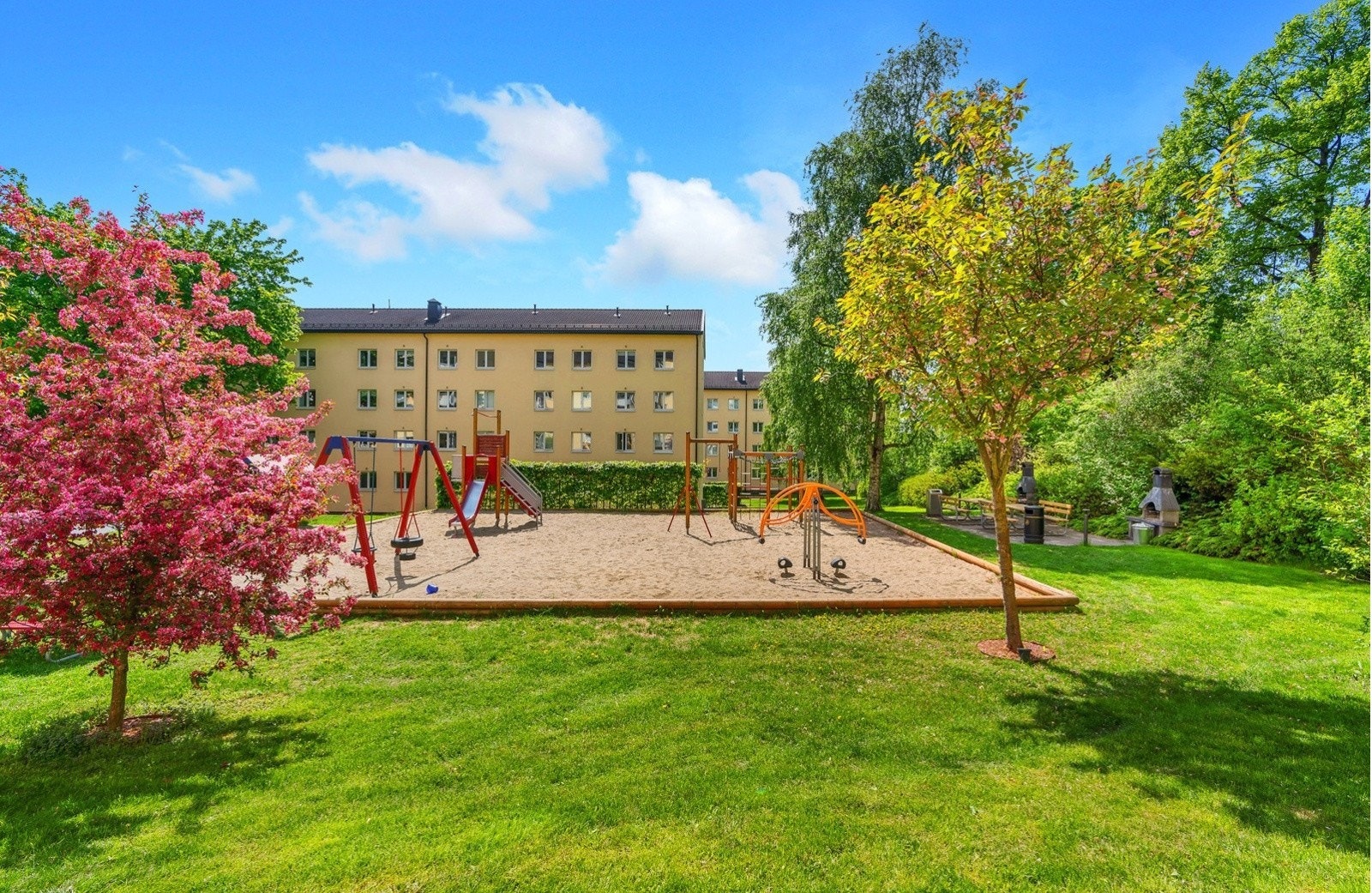 Leiligheten er omringet av frodige omgivelser på sommerstid. Tomten er pent opparbeidet med velstelt gressplen, sittegrupper, trær og busker. Galleribilde