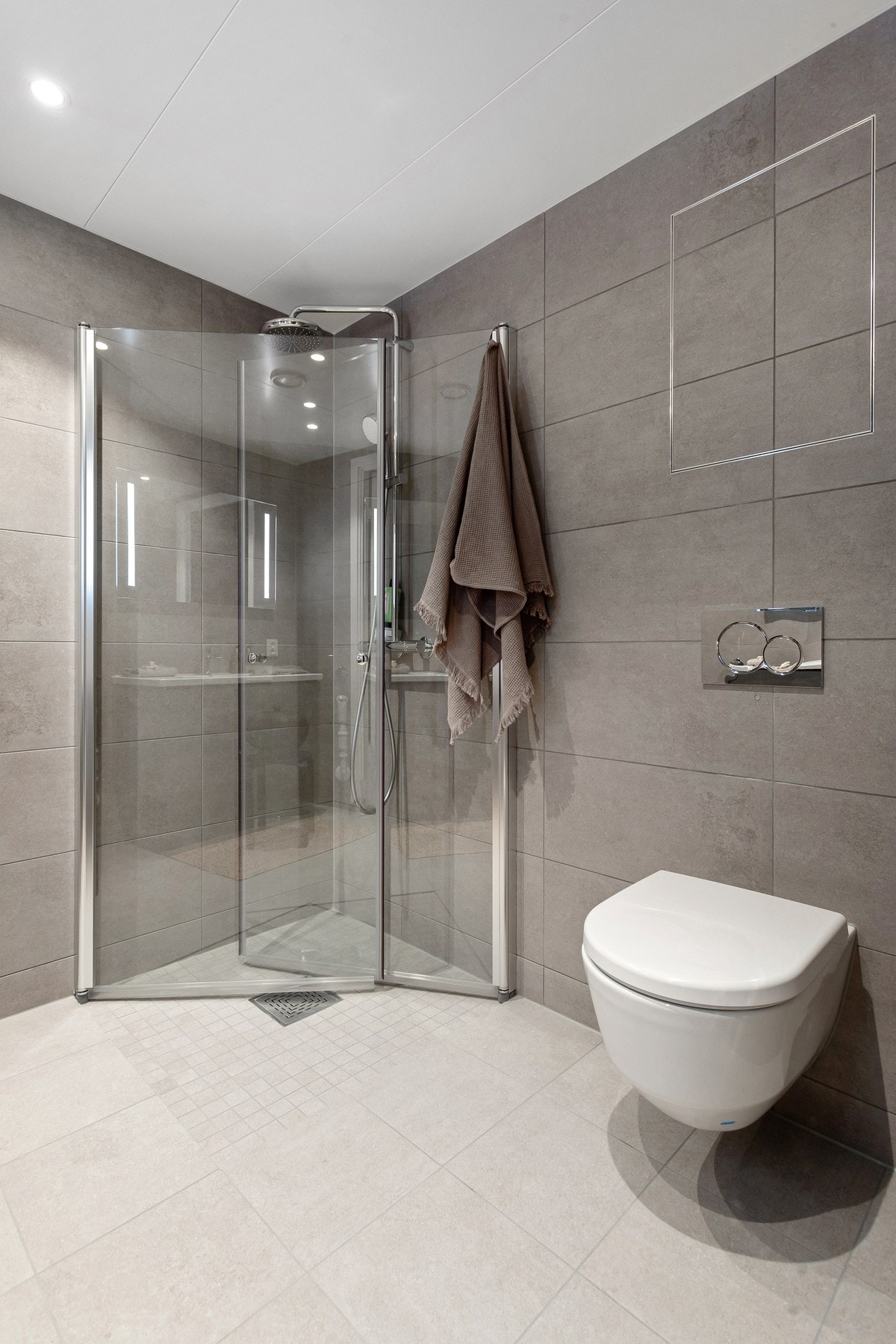 Baderommet er også utstyrt med dusjhjørne med innfellbare glassdører og både hånd- og regnfallsdusj fra Grohe, samt vegghengt toalett. I hjørnet er det plass og opplegg for vaskemaskin og tørketrommel over om ønskelig. Galleribilde