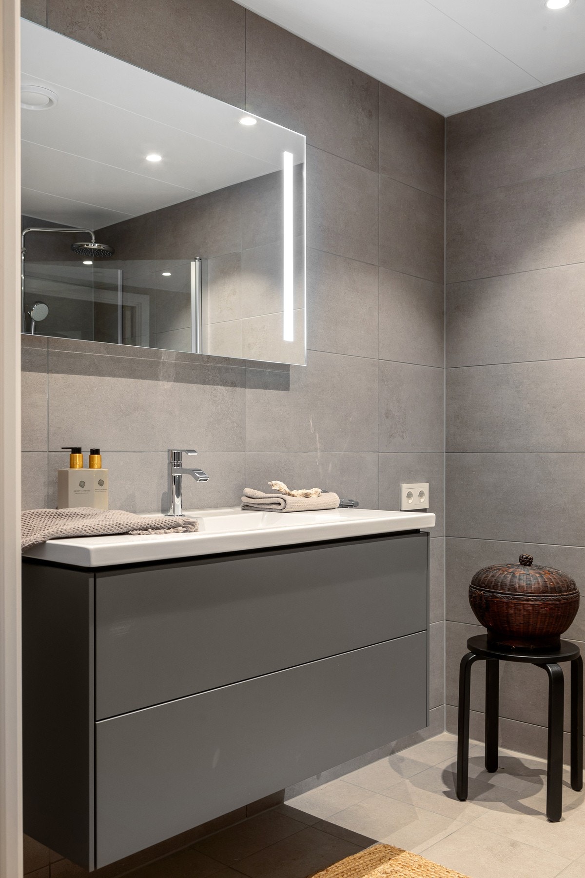 Moderne baderomsinnredning fra Lind med to grepsløse skuffer (push open funksjon) og heldekkende servant med servantbatteri fra Tapwell. Over innredningen er det et stort vegghengt speil fra Lind med integrert LED-lys. Galleribilde