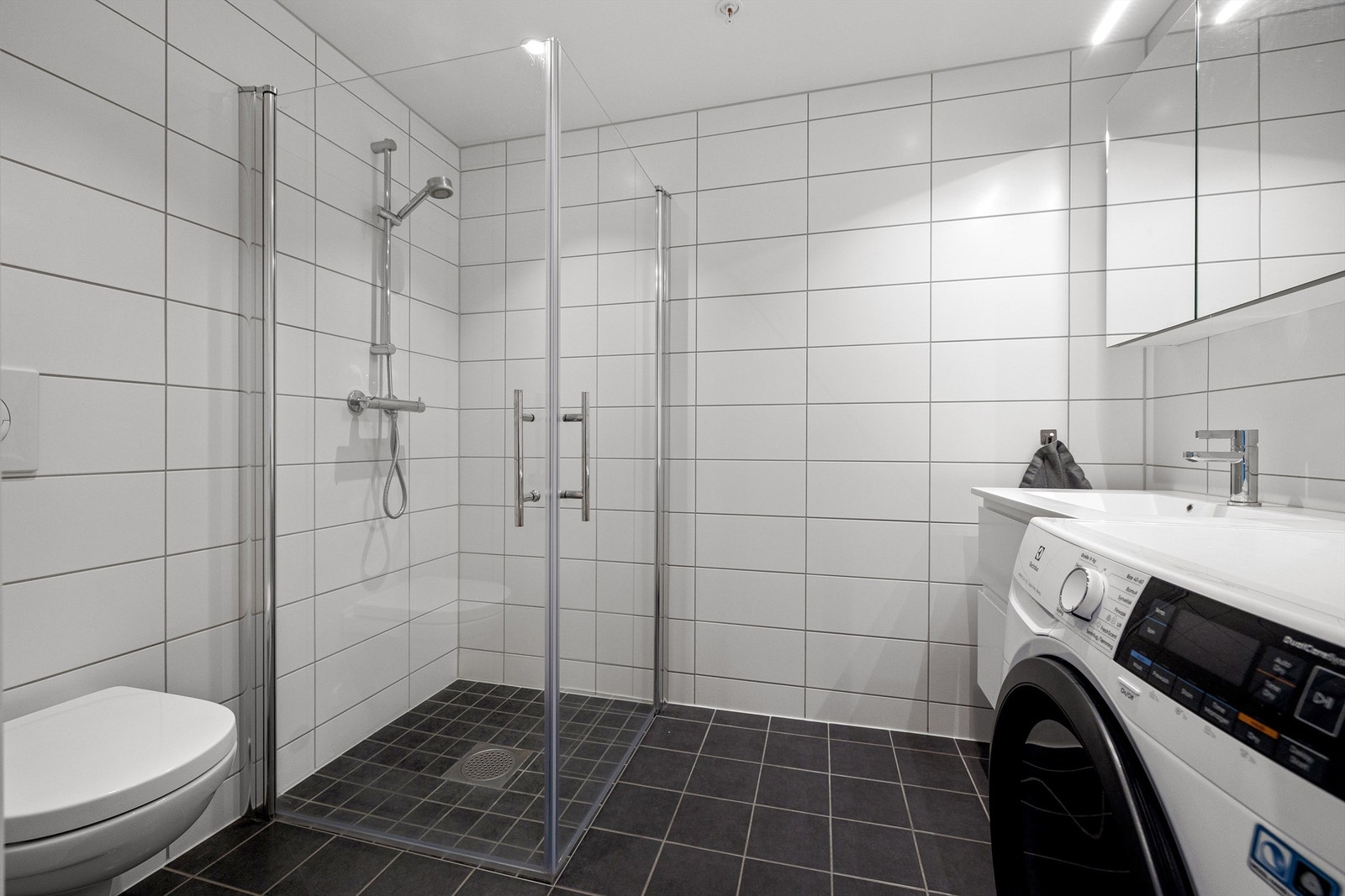 Flislagt gulv med gulvvarme og flislagte vegger. Nedsenket himling med downlights Galleribilde