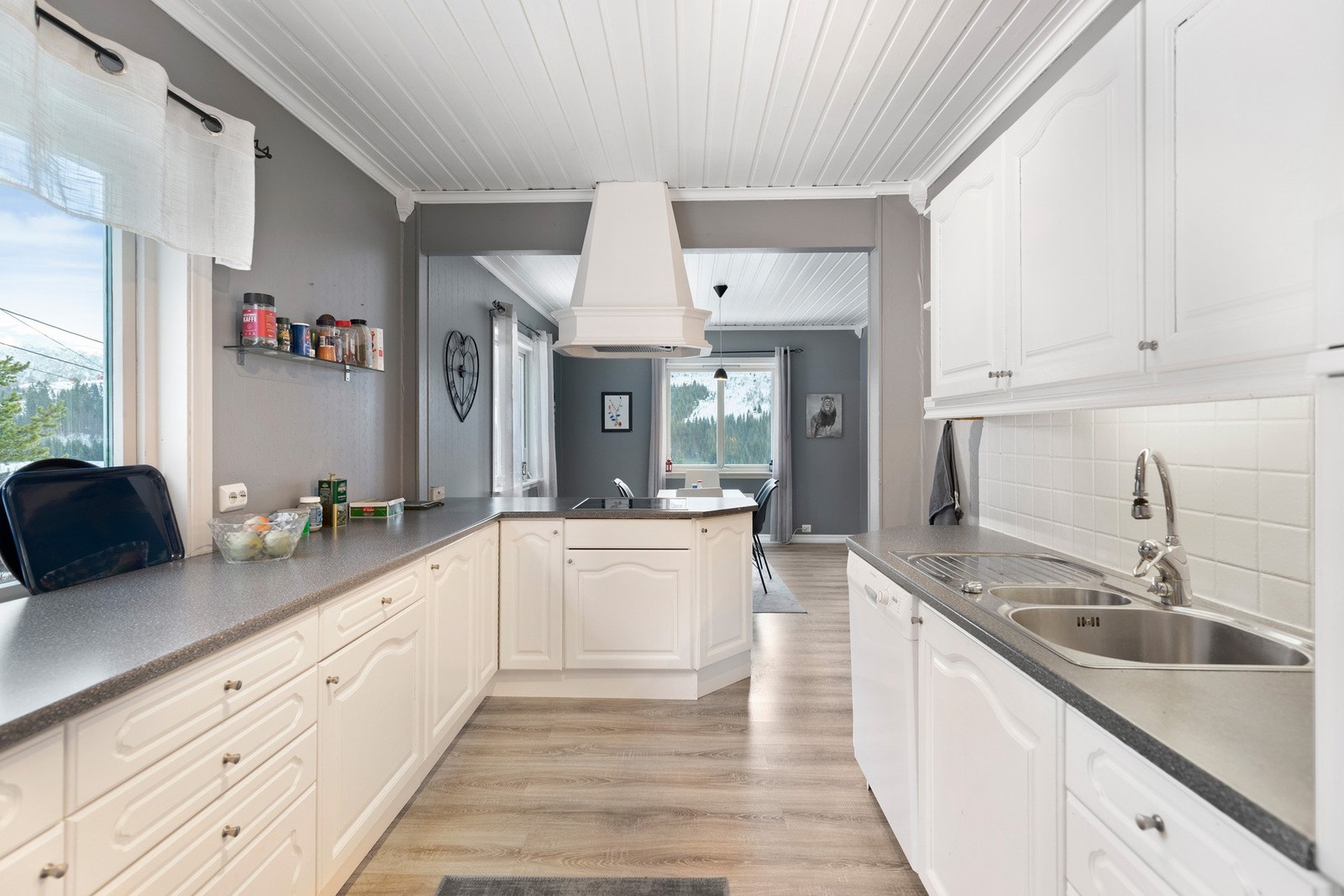 Innredningen har hvite, profilerte fronter og er utstyrt med integrert komfyr og platetopp, samt opplegg for oppvaskmaskin og nisje for kjøleskap Galleribilde