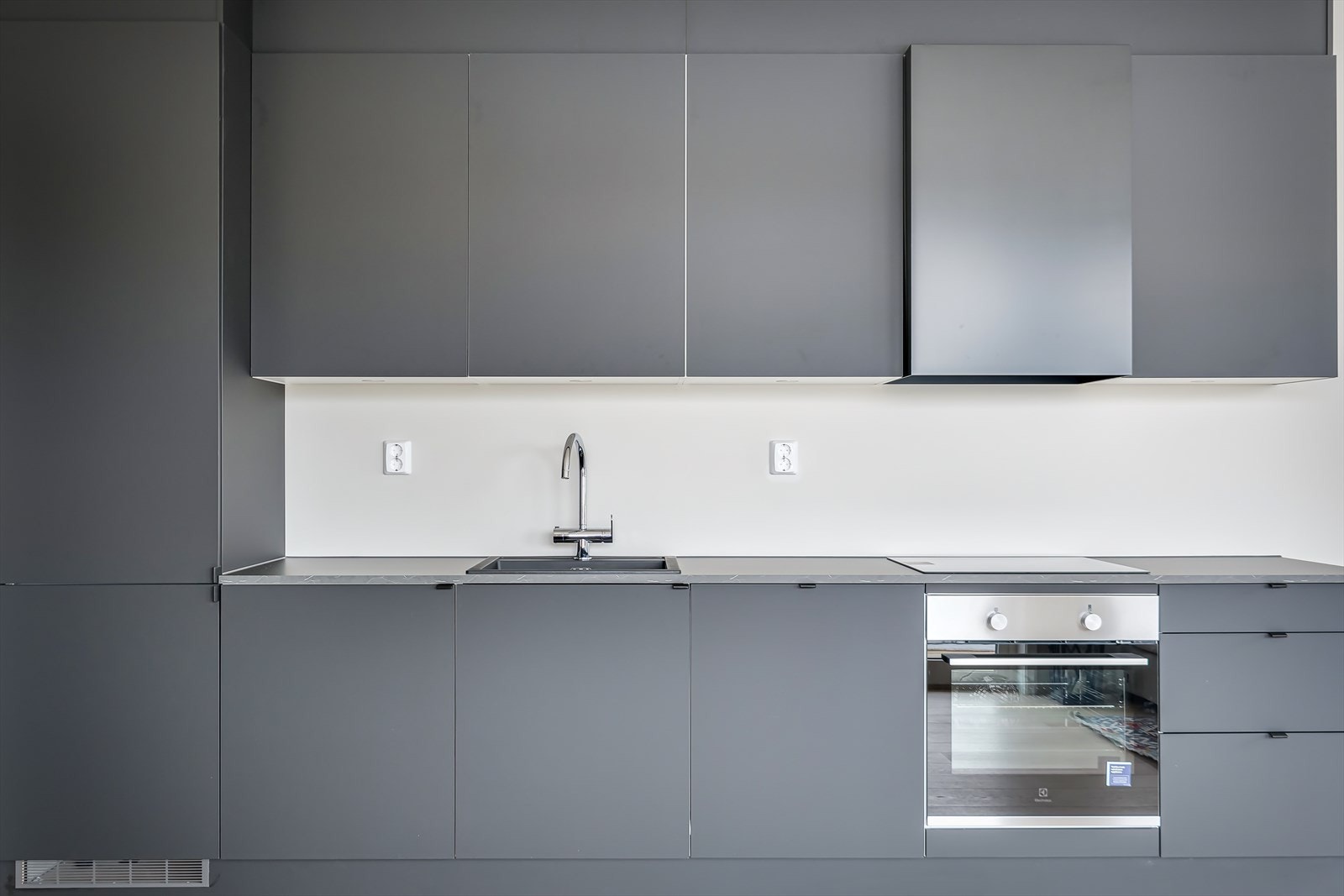 Integrerte hvitevarer som stekeovn, induksjonskoketopp med ventilator over, oppvaskmaskin og kjøleskap/frys. Galleribilde