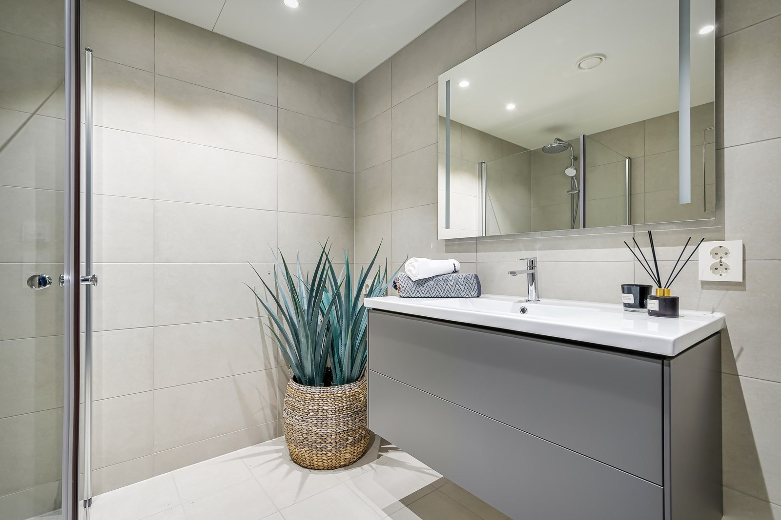 Badet består av dusjhjørne med glassvegger og veggmontert armatur, servant med underskap og speil med integrert belysning. Det er opplegg og plass til vaskemaskin og tørketrommel. Galleribilde