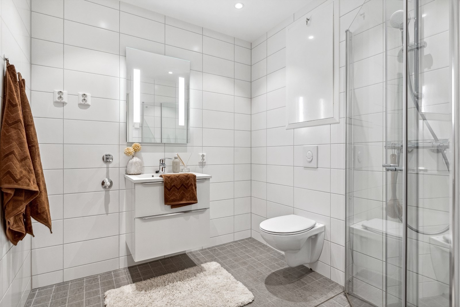 Dagene får en god start på et flislagt bad med downlights, vegghengt toalett og opplegg for vaskemaskin. Galleribilde