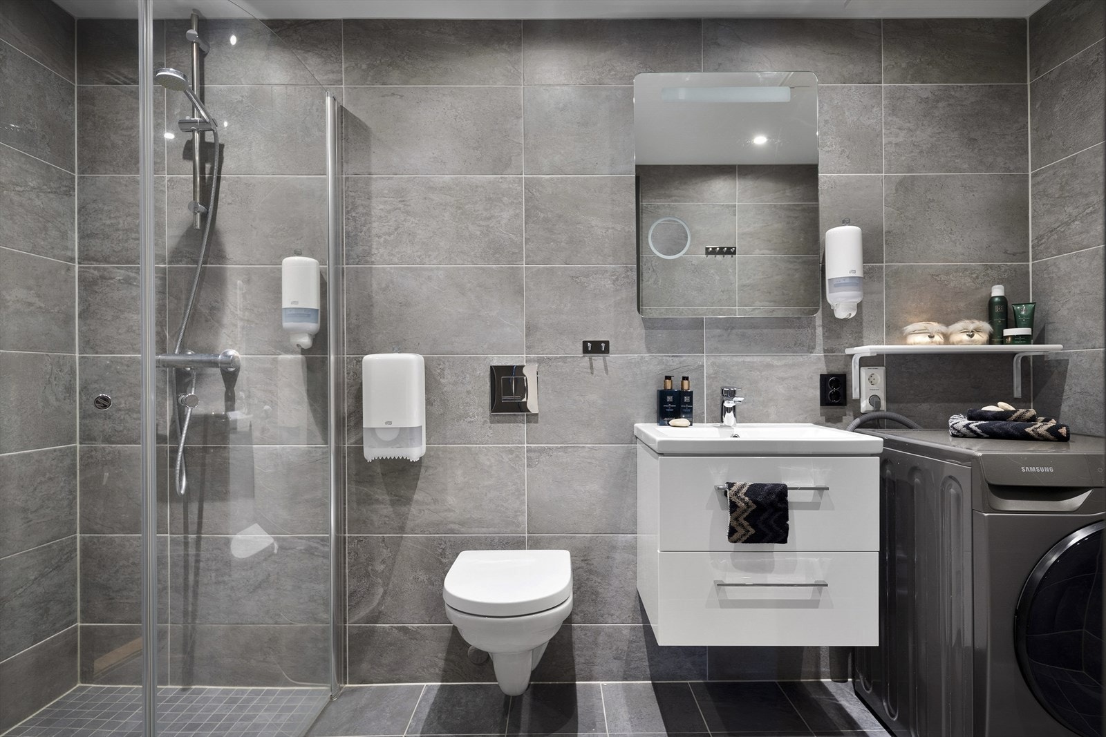 Badet er innredet med servant med skap, speil med belyning og vegghengt toalett. Det er også opplegg og plass til vaskemaskin. Galleribilde