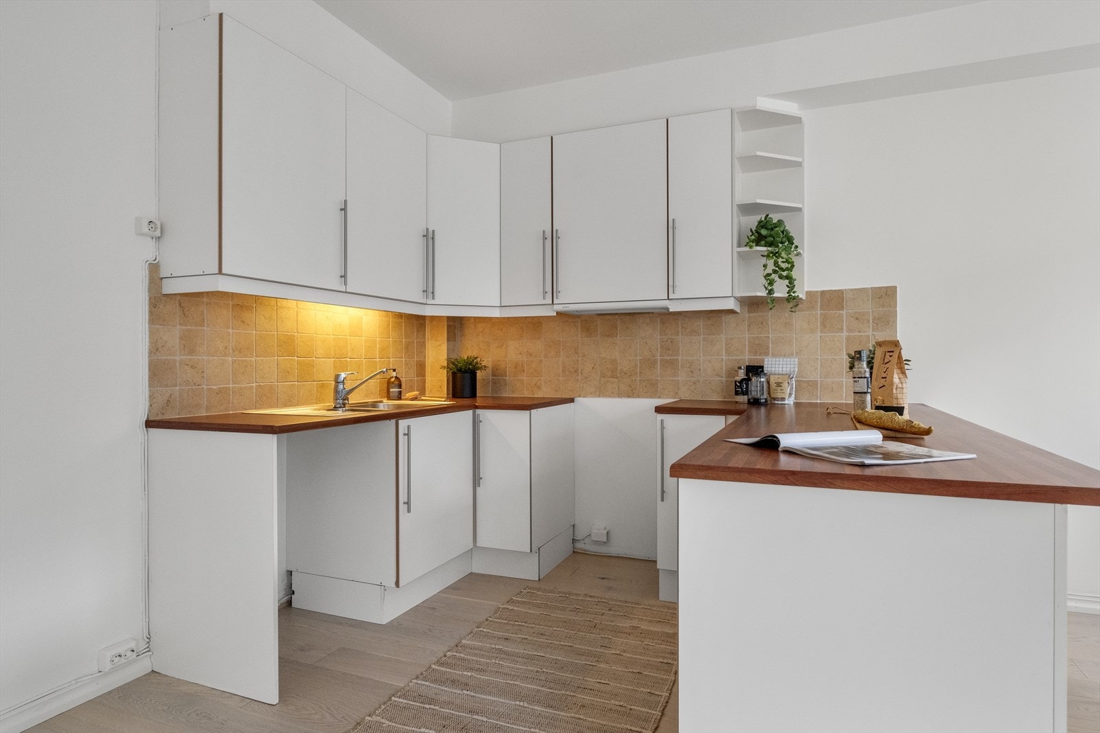 Pen og lys kjøkkeninnredning med godt med skap og benkeplass. Galleribilde