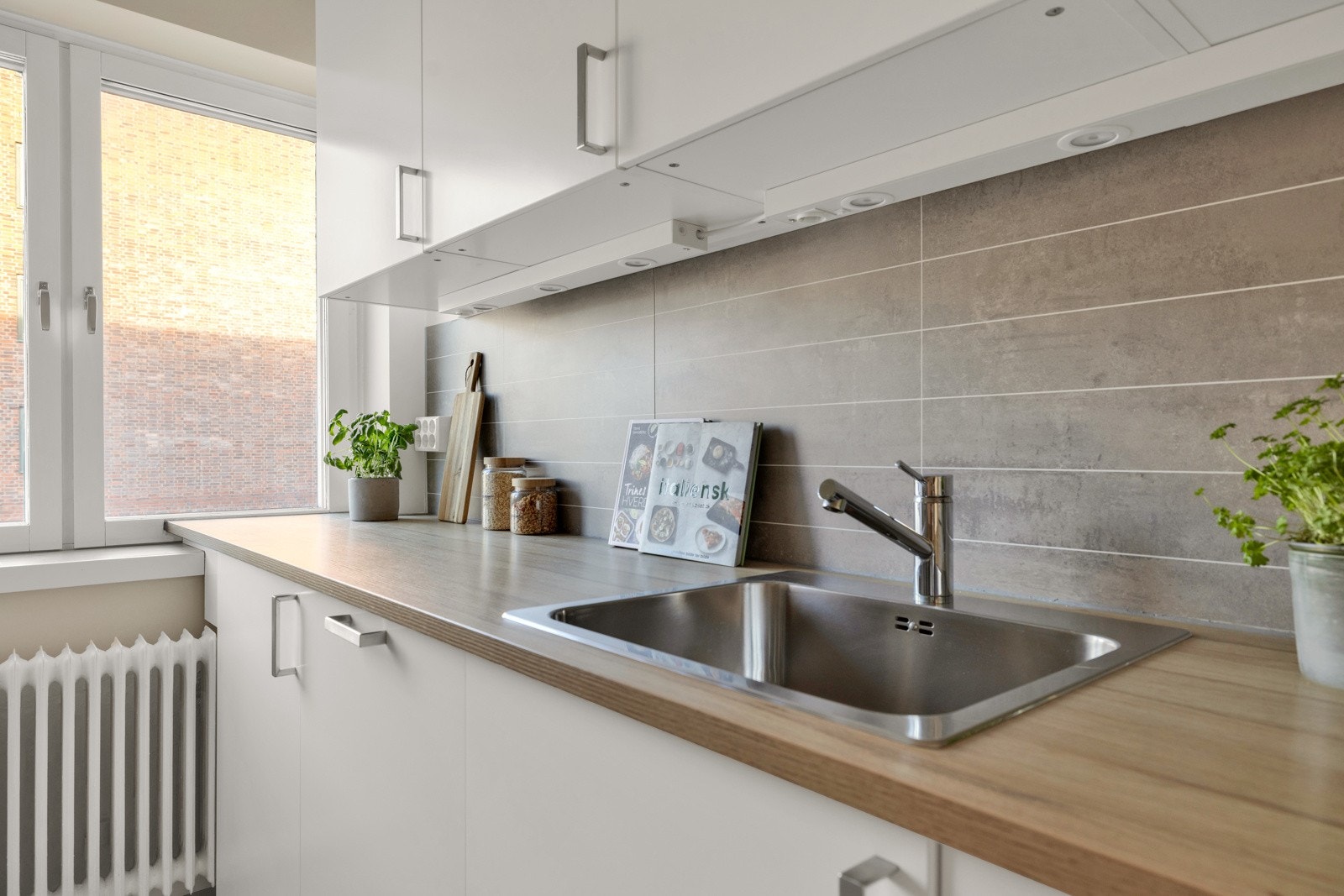 Innredning med hvite, glatte fronter og laminert benkeplate. Stilige kjøkkenplater over benk. Galleribilde