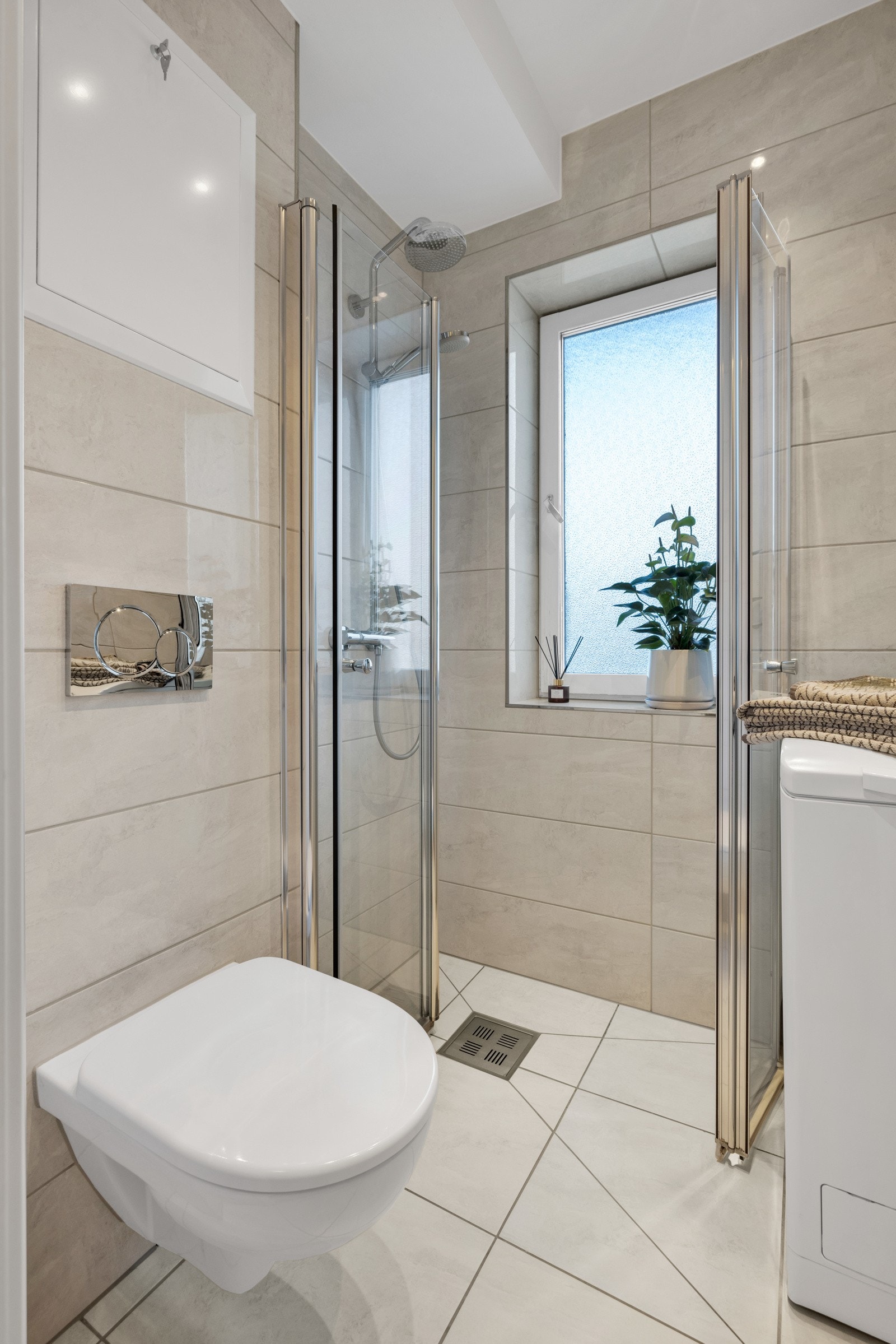 Badet har vegghengte dusjdører i glass, samt vegghengt toalett. Galleribilde