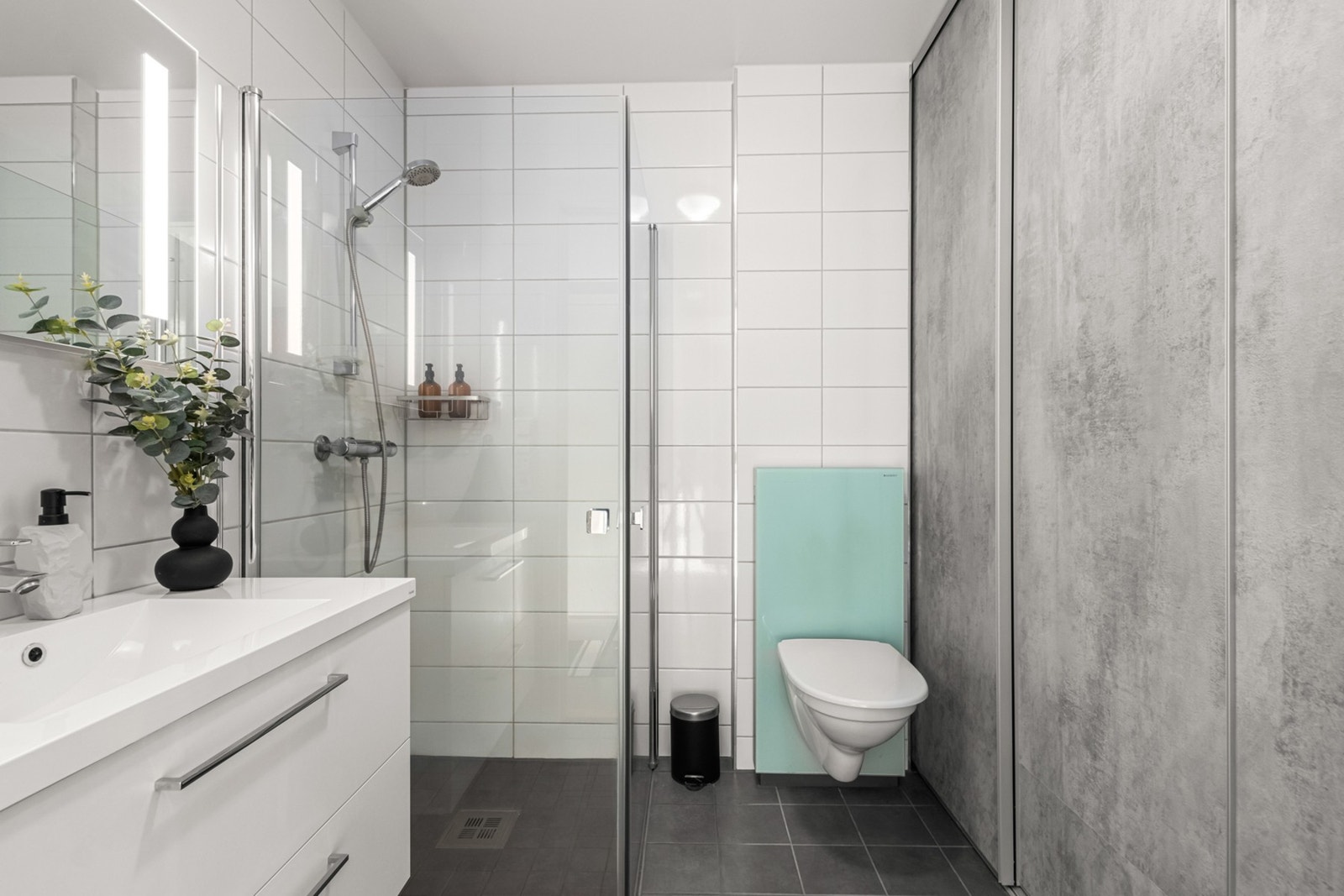 Flislagt bad med gulvvarme - bak skyvedør er det opplegg for vaskemaskin, varmtvannsbereder, fordelingsskap vann og vannbåren gulv-varme. Galleribilde