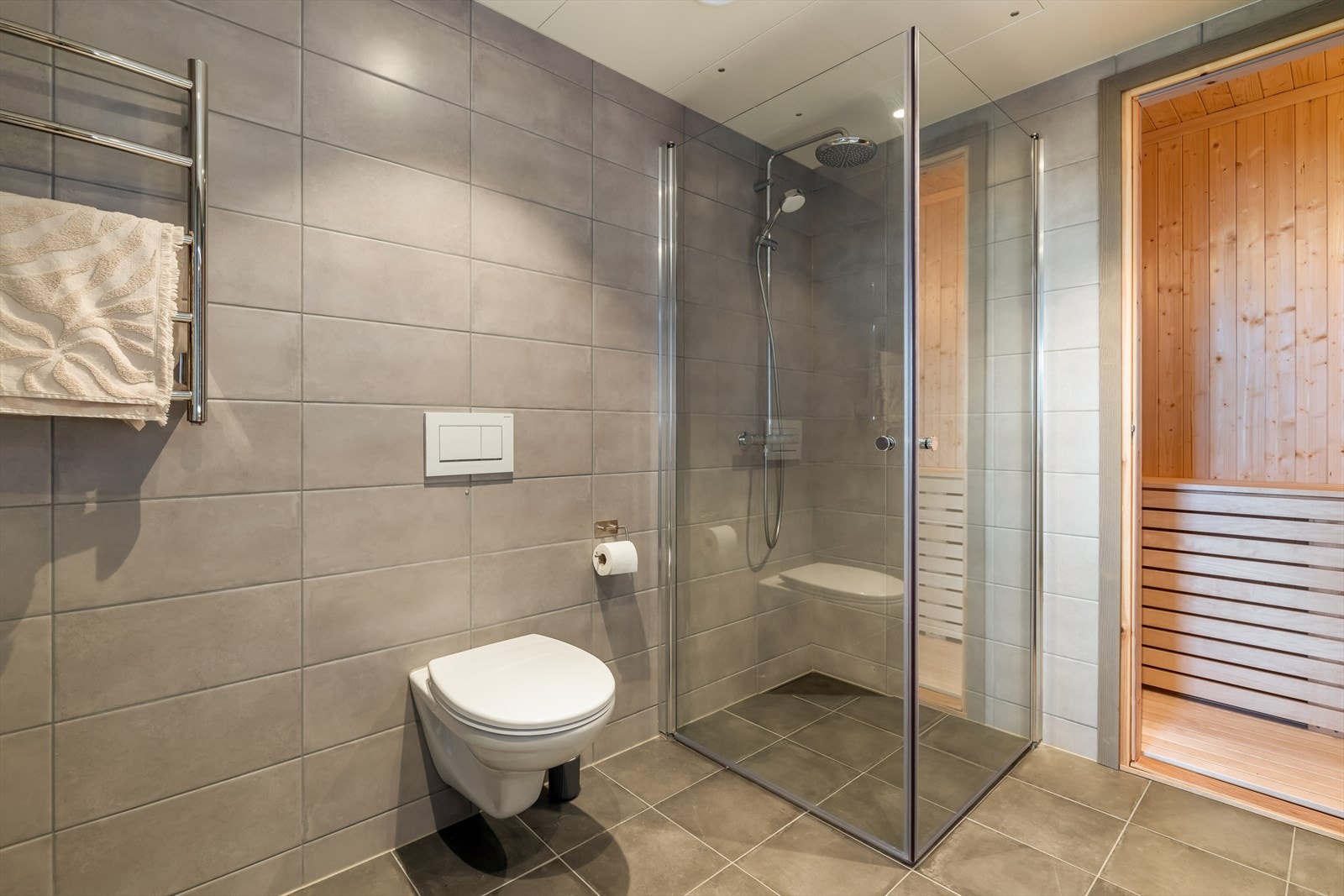 Badet har også dusjhjørne med vegger og vegghengt toalett, samt håndkletørker og varmekabler i gulv. Galleribilde
