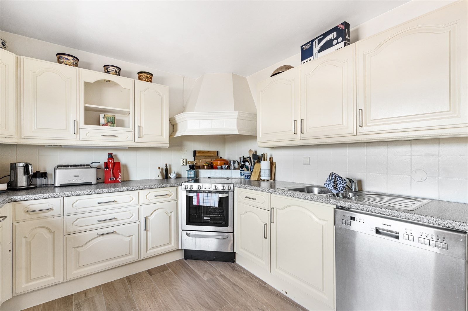 Kjøkkeninnredningen har malte profilerte fronter, laminat benkeplate og fliser på bakvegg. Frittstående komfyr og vaskemaskin. Galleribilde