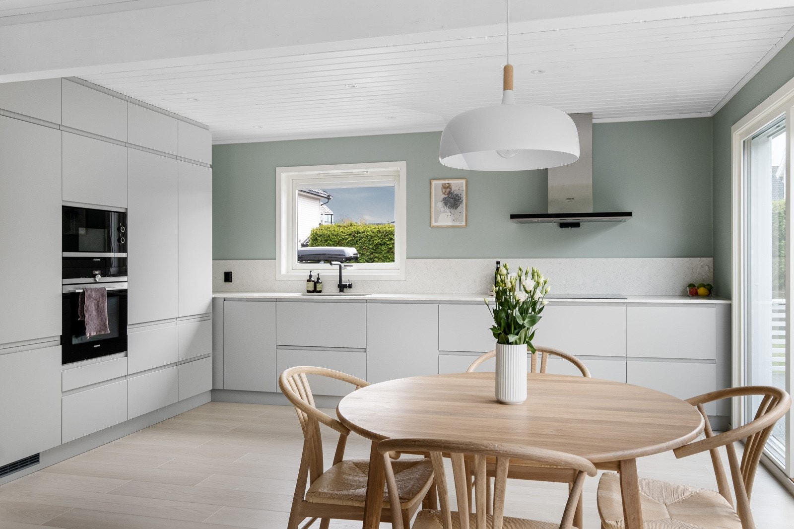 Alle hvitevarene er integrerte for å gi en sømløs estetikk. Kjøleskapet med frysedel, komfyr og mikrobølgeovn er pent innfelt i høyskapene. Galleribilde