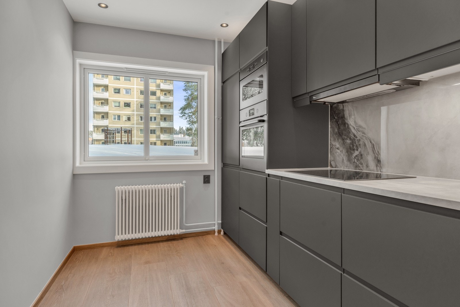 Velfungerende kjøkken med downlights i himling og vindusflater som slipper inn naturlig lys Galleribilde