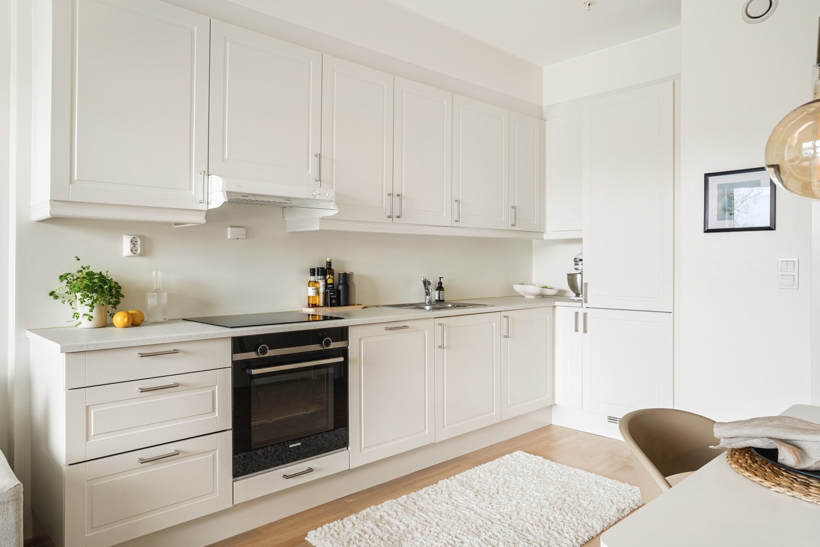 Kjøkkeninnredning med slette fronter, laminat benkeplate, over benkeplaten er det benyttet malte flater, stål. Galleribilde