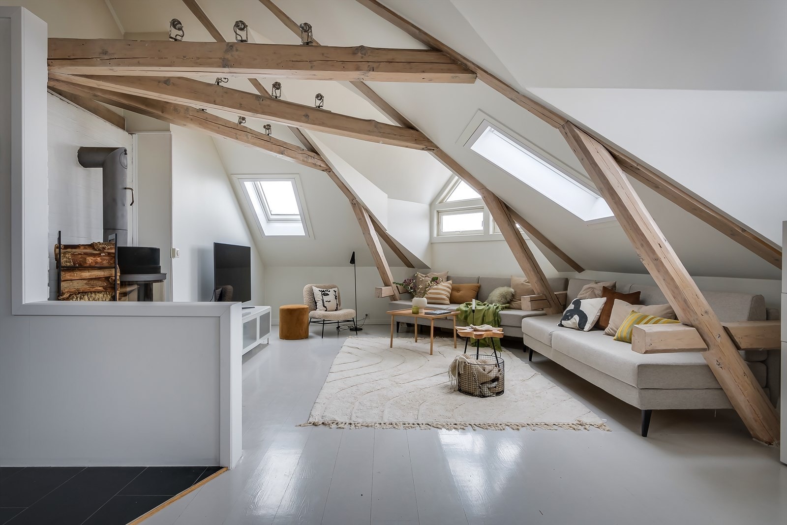 De originale trebjelkene gir leiligheten karakter og skaper en fin balanse mellom det moderne og det sjarmerende. Galleribilde