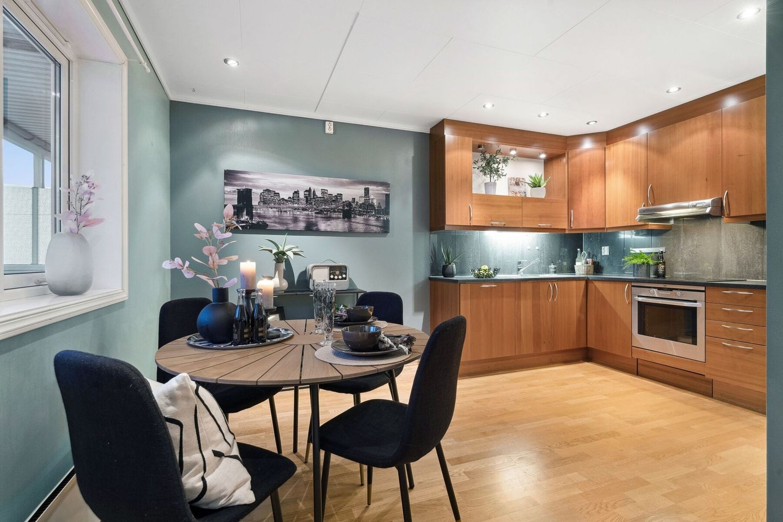 Kjøkkenet ligger noe tilbaketrukket fra stua bak vegg. Downlights i himling. Galleribilde