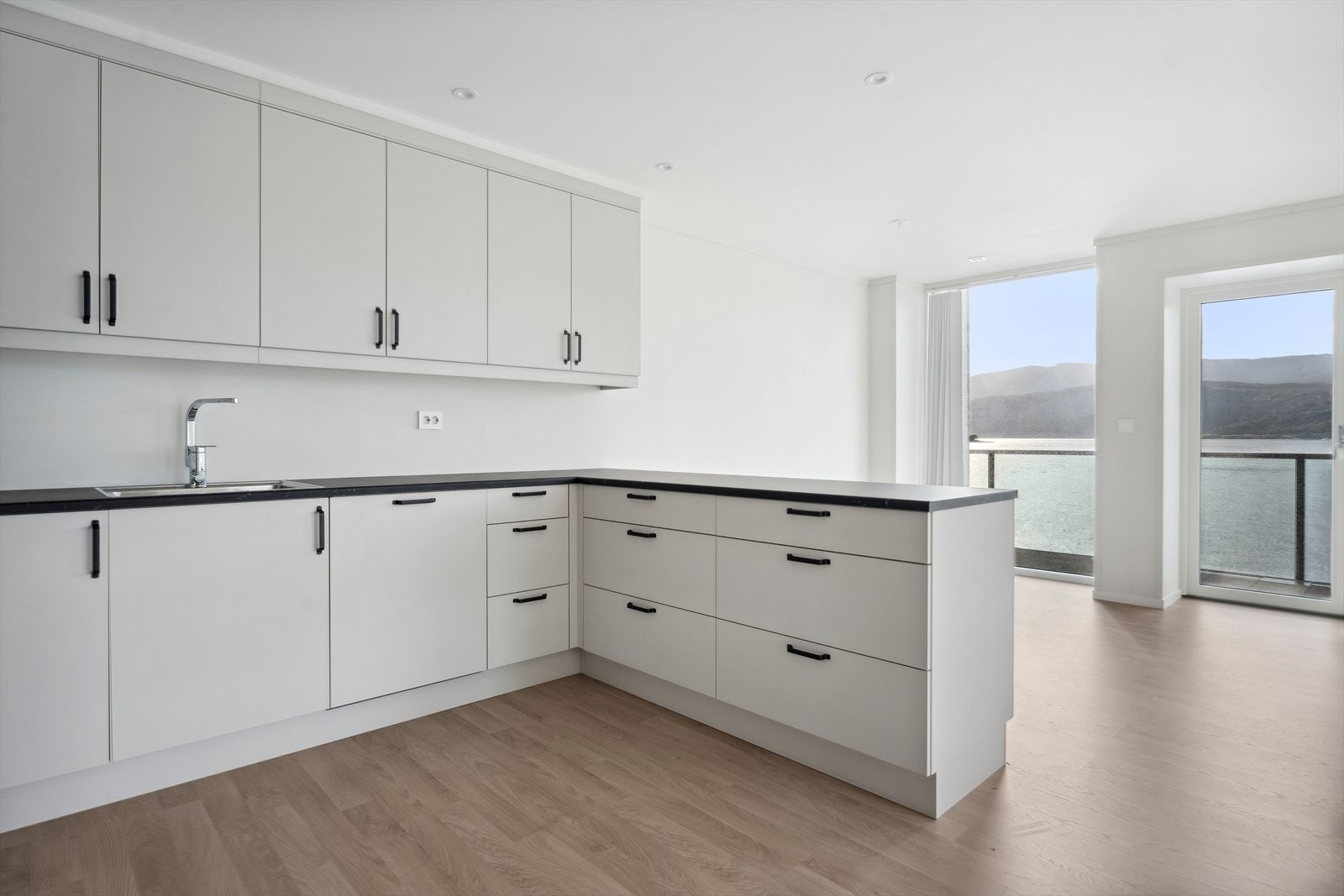 Godt med skap-, skuffe og overskap til himling, kvite, slette frontar og benkeplate i laminat. Galleribilde