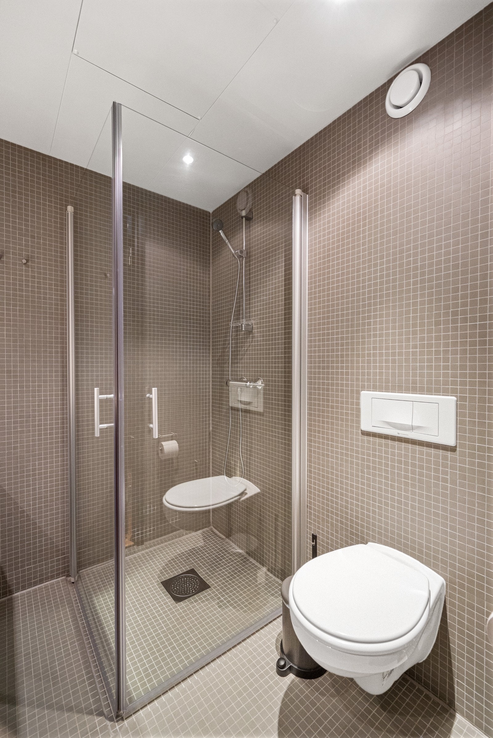 Elegant baderom flislagt med mosaikkfliser, komplett med varmekabler for ekstra komfort. Galleribilde