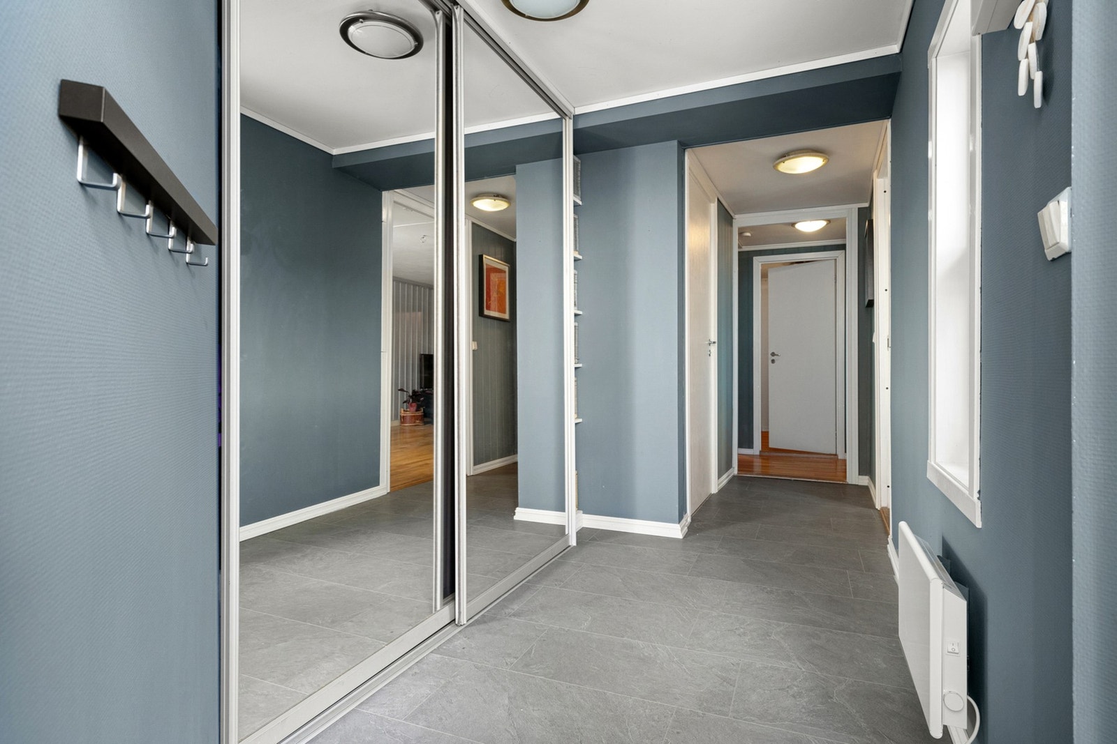 Lys og innbydende gang med praktisk skyvedørsgarderobe med god plass til oppbevaring av yttertøy. Galleribilde