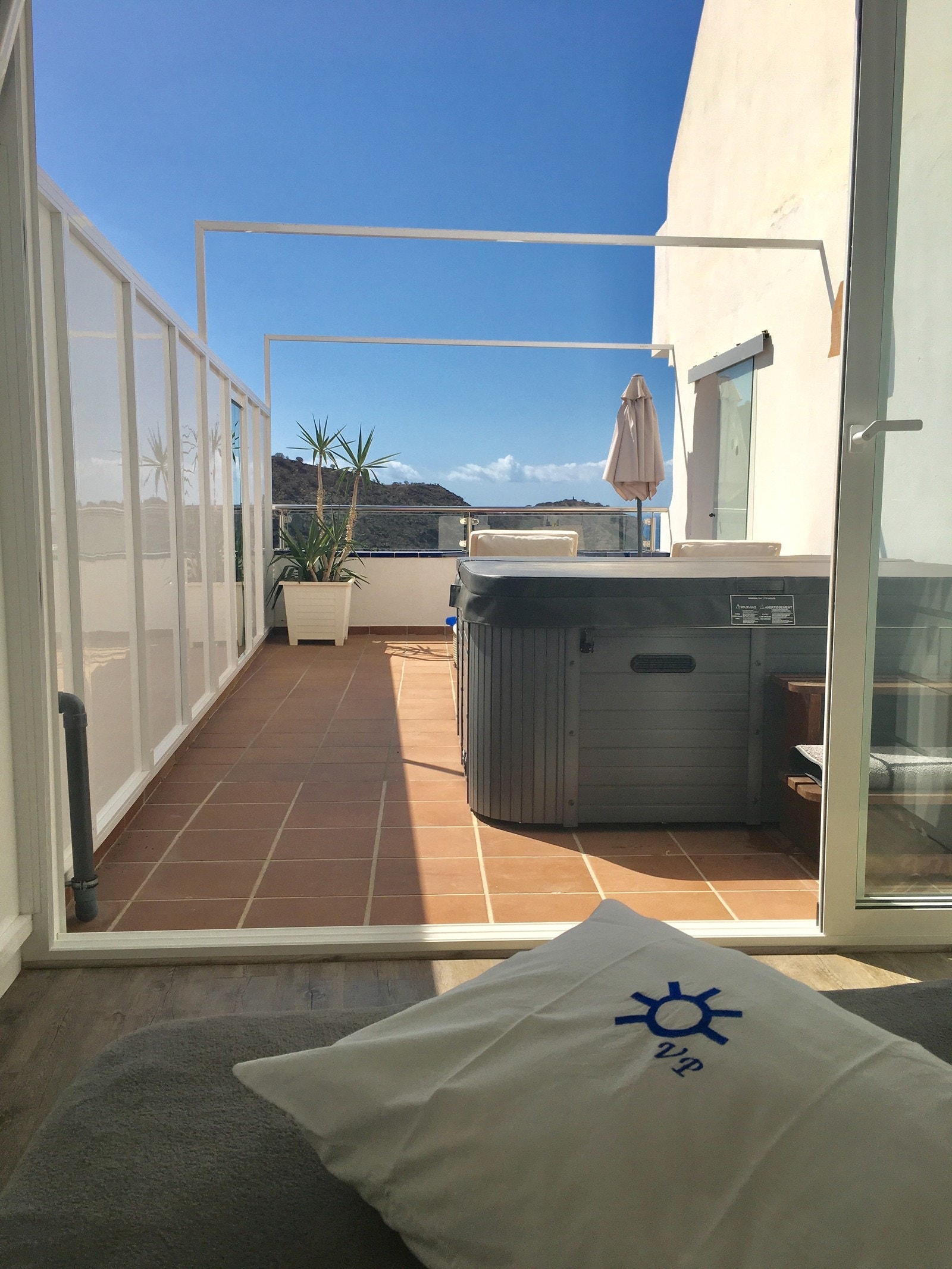 303 Tatt fra ekstra soverom og ut mot terrassen med jacuzzi og solsenger - her er det under åpen himmel. Galleribilde