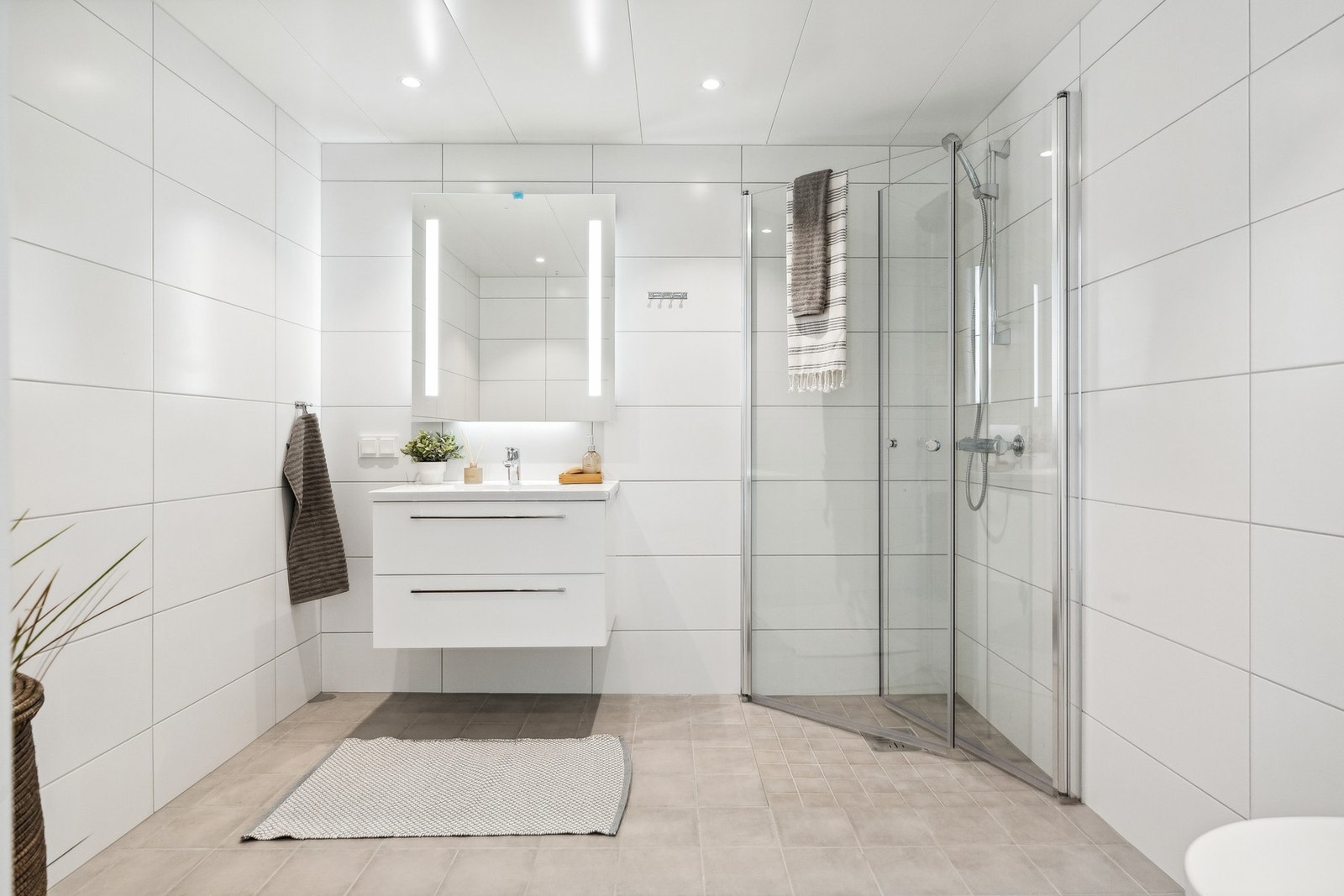 Vakkert baderom innredd med dusjhjørne med innfellbare dører i glass, servant med underskap, speil og toalett. Badet har varme i gulv. Galleribilde