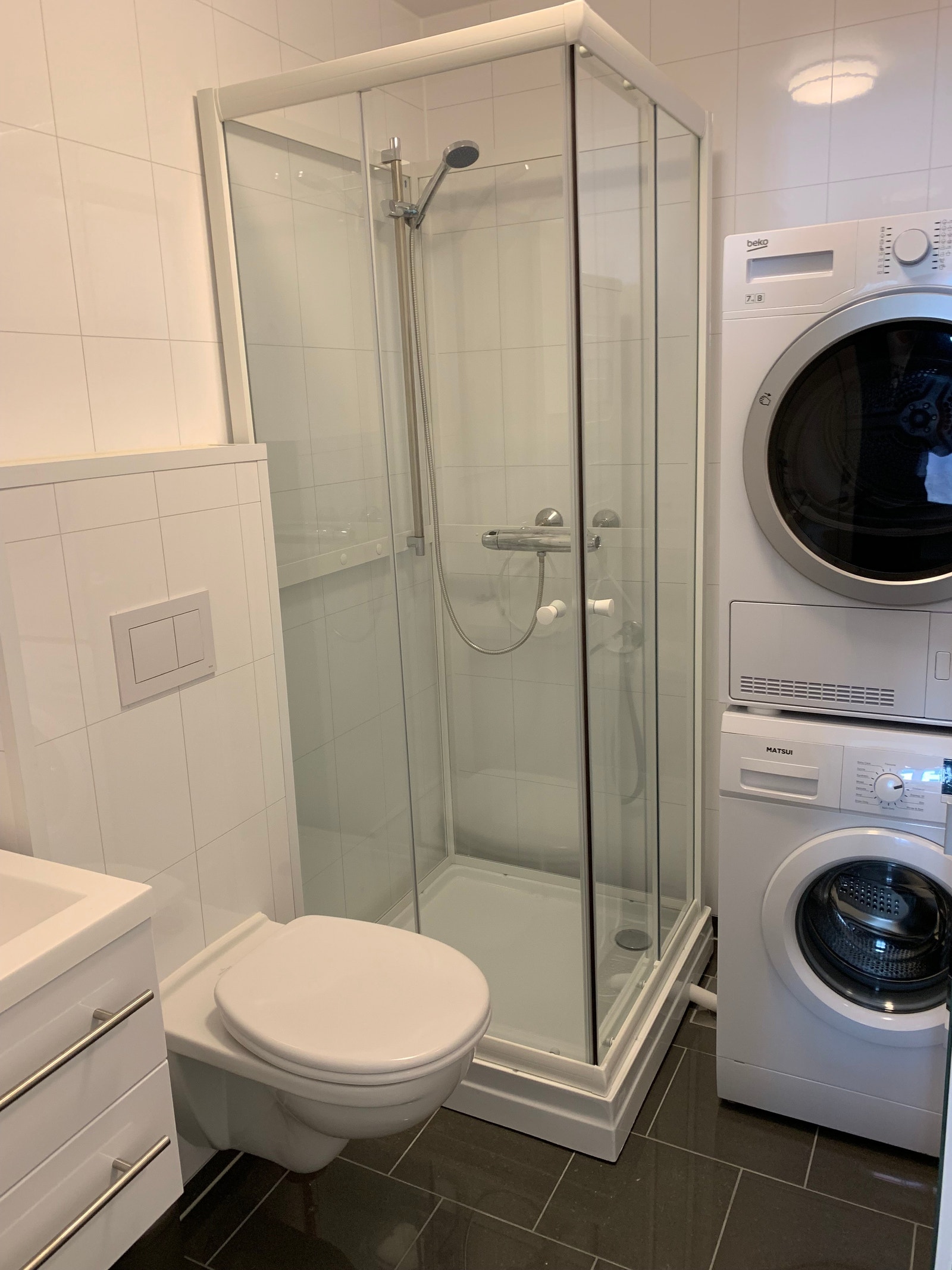 Bad i huset, med dusj, toalett, vask, vaskemaskin/tørkemaskin, flislagt og varme i gulv Galleribilde