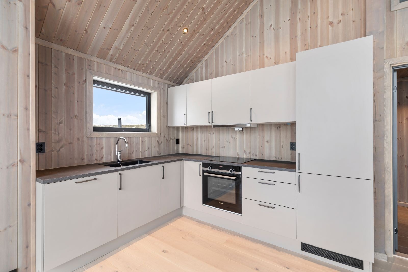 Kjøkkeninnredning med komfyr, koketopp og innebygd kjøleskap. Galleribilde