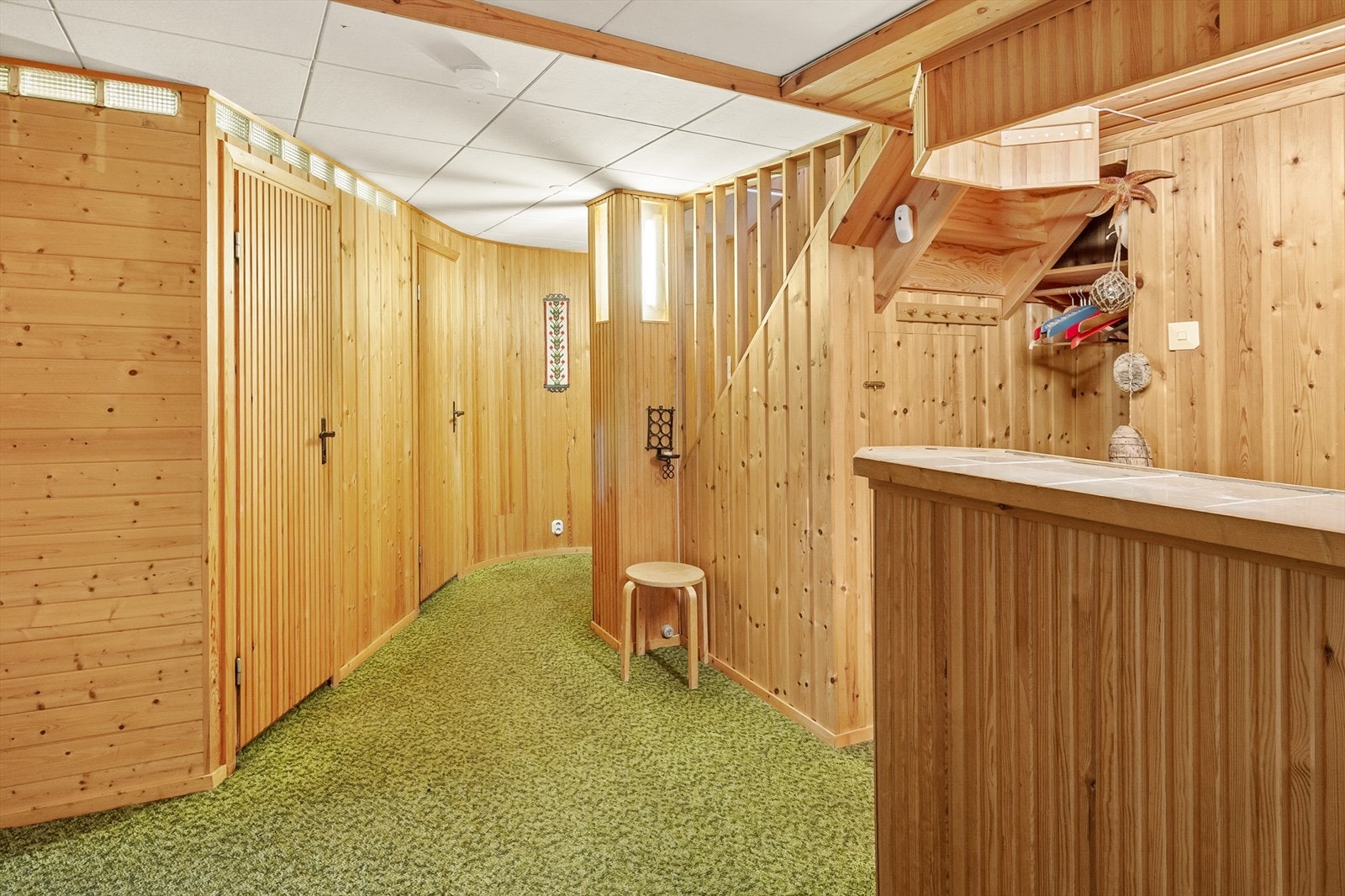 Gang/trapperom med teppe på gulv, panel på vegger og takplater i tak. Galleribilde