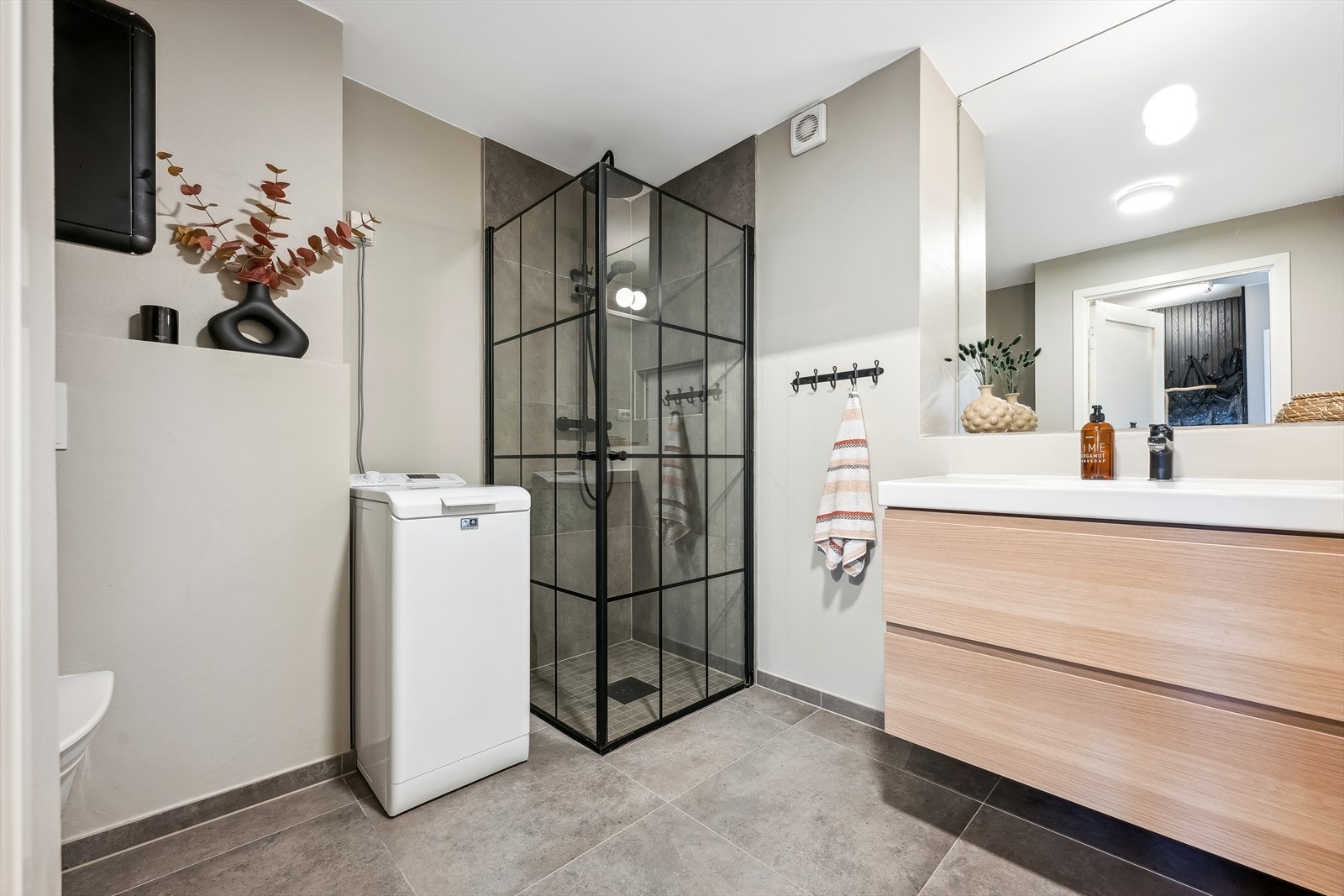 Bad/vaskerom er utvidet fra opprinnelig løsning og er fliselagt med tidsriktige fliser (2019). Det er varmekabler i gulvet, baderomsinnredning, vegghengt toalett og et lekkert dusjhjørne. Opplegg for vaskemaskin. Et godt sted å starte dagen! Galleribilde