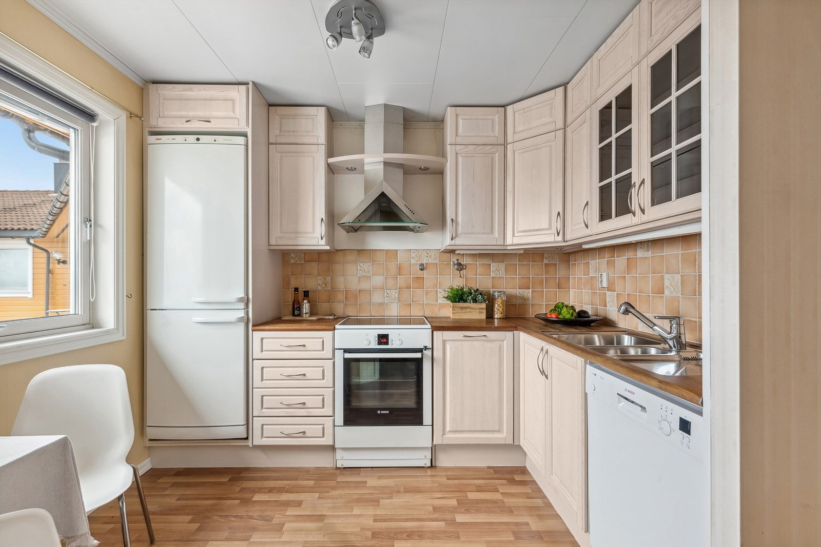 Flott kjøkken med vinklet innredning og plass til frittstående hvitevarer. Galleribilde