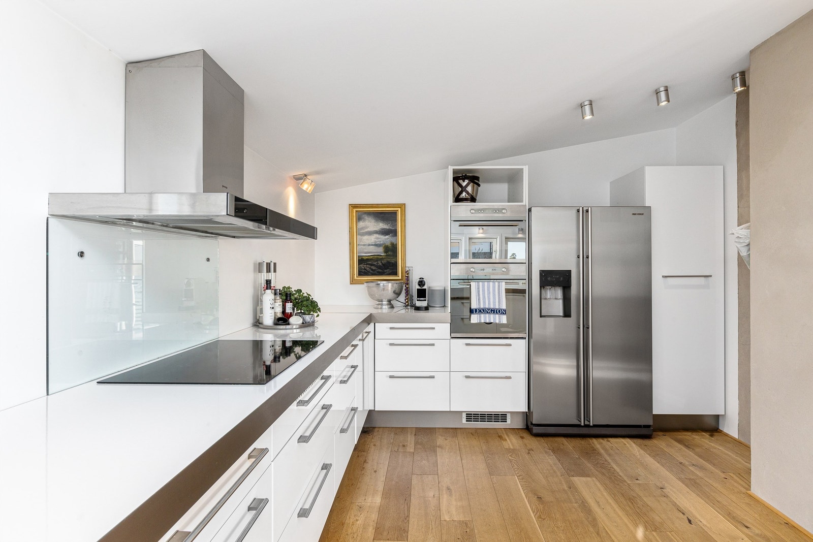 Det er hvit IKEA-kjøkkeninnredning med glatte fronter og benkeplater av laminat. Galleribilde